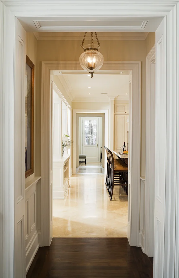 For this custom-built traditional home, we worked closely with the architect to refine the millwork details, then worked with the owners to place and enhance their existing furnishings and art collection. Our use of layers and repetition to enhance transitions between spaces is seen in this view of the main hall looking across the house through the kitchen.