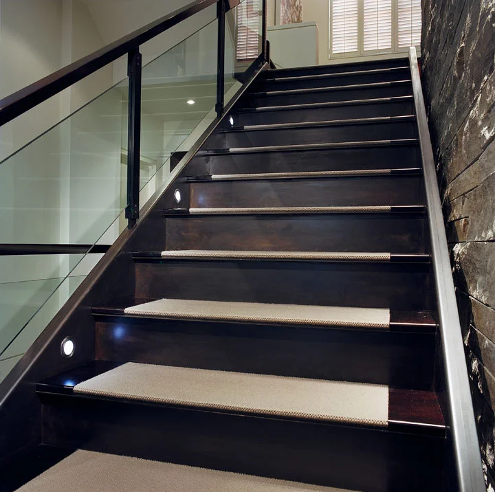 The central steel stair floats against the stone wall, connecting seamlessly with wood landings on one continuous stringer, which incorporates LED lighting. The finely detailed glass and steel railing creates a visual lightness to the massive, yet elegant, structure.