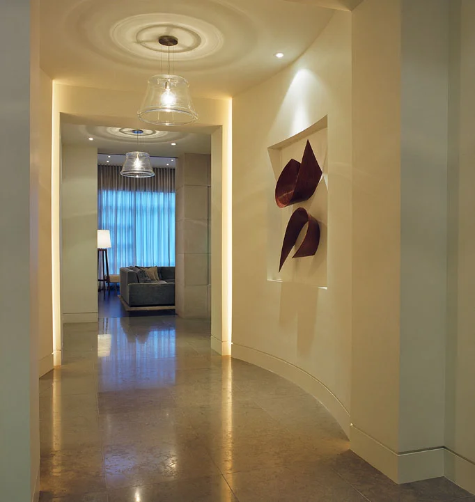 In the dramatic and welcoming entry, curved walls embrace visitors and break up the long hall, while repeated pendants provide continuity and rhythm.