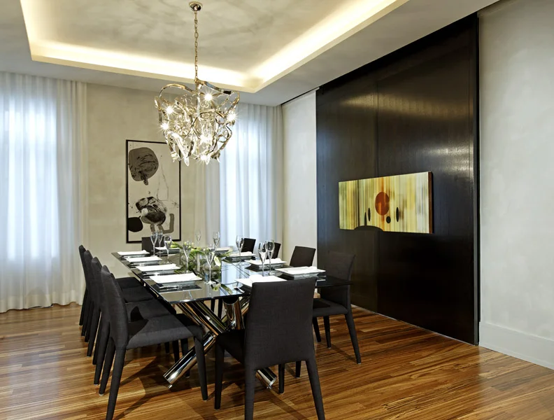 Both gracious entertaining and intimate family life are supported and enhanced by this modern but warm and timeless surrounding. The gathered sticks table base, twisted metal pendant and art finished walls animate this minimalist dining room, separated from the living room by double layered sliding doors, which simulate an unbroken wall when closed.