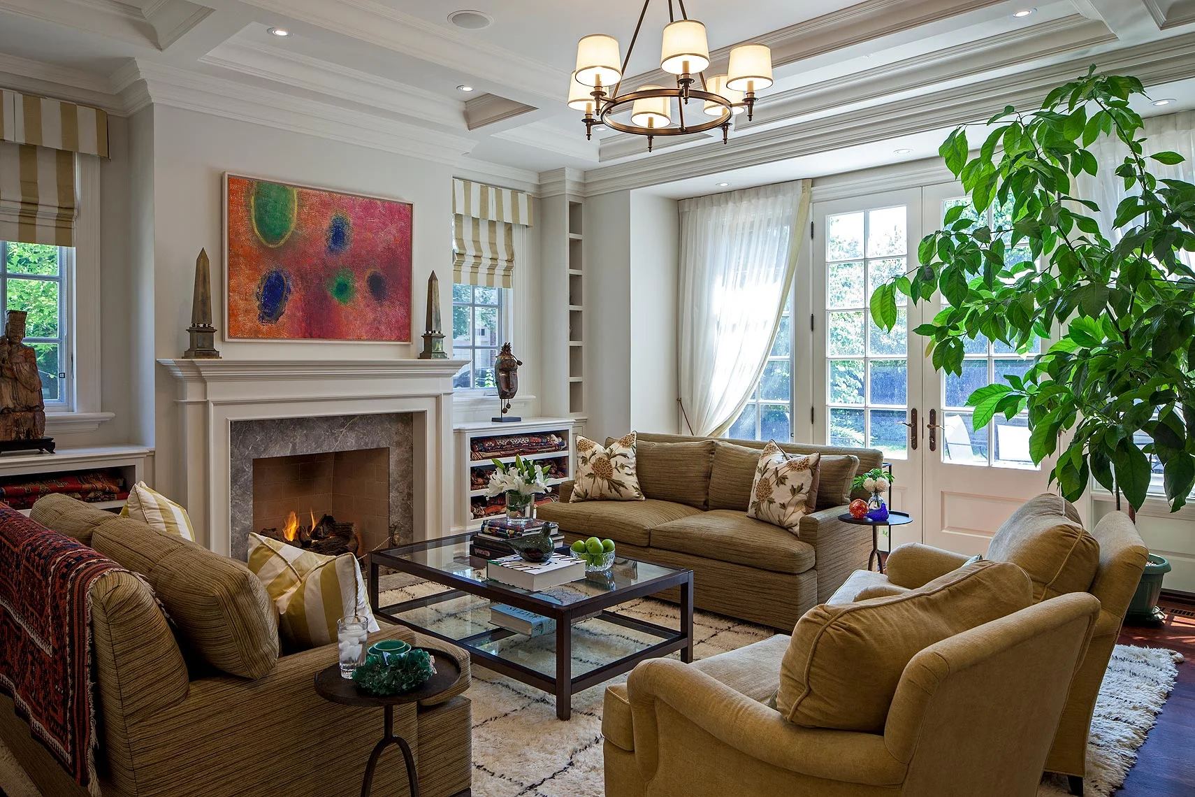 Perfectly symmetrical, the complex wall and ceiling details are both elegant and functional. The marble fireplace centres a carefully planned storage wall that flanks the windows with small niches housing gemstone specimens collected by the owners, both geologists. The painting is “Celestial Gathering” by historical Canadian artist Michael Forster. Below a historic sculpture and mask, large shelves provide storage for several antique carpets. The coffee table and seating were existing; new upholstery stands up to use by children and pets, as does the handmade Jan Kath carpet. The crewel work cushion covers reflect the owner’s love of textiles.