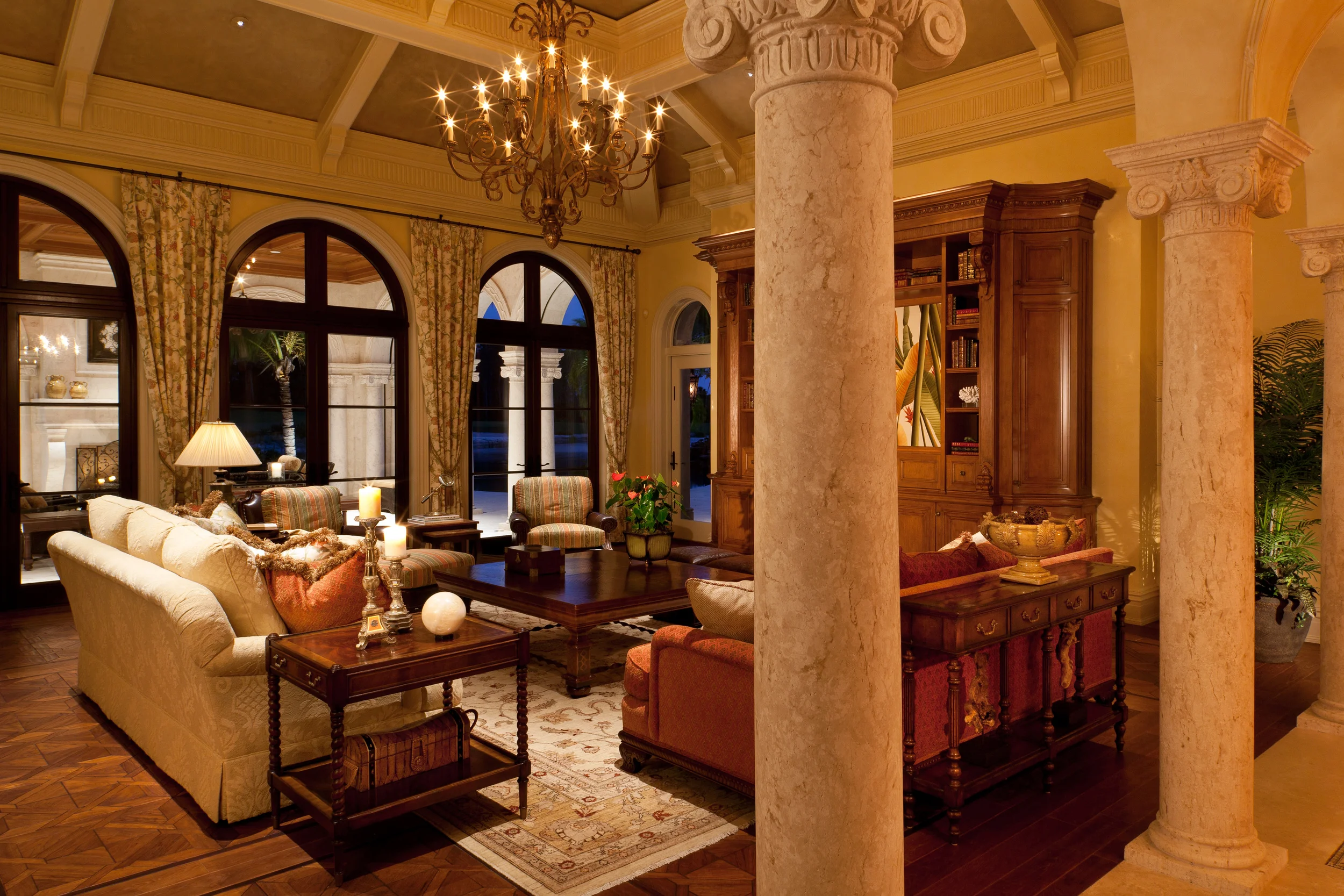 Opening onto the lanai, the family room of this lovely Florida home also connects to dining room across the elegant colonnade of solid carved Syrian stone. The columns and the intricate ceiling structure were all carefully planned and detailed. So, too, was the massive 12 foot tall wall unit, which was executed in select hard white maple finished with multiple glazes that create its warm character.