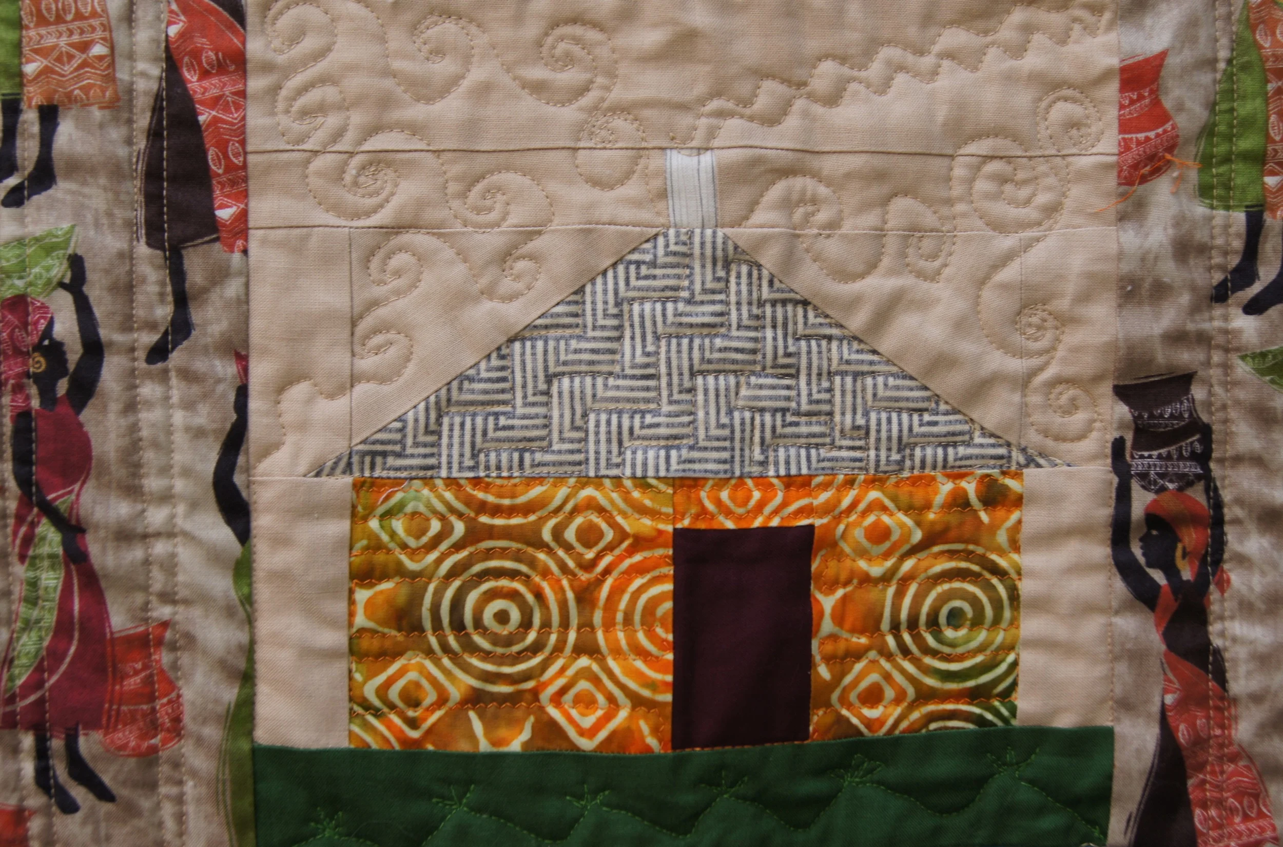 Central hut showing serpentine stitch for smoke. Also note the straight stitching done on the focus fabric blocks adjacent to the block and on the hut walls.