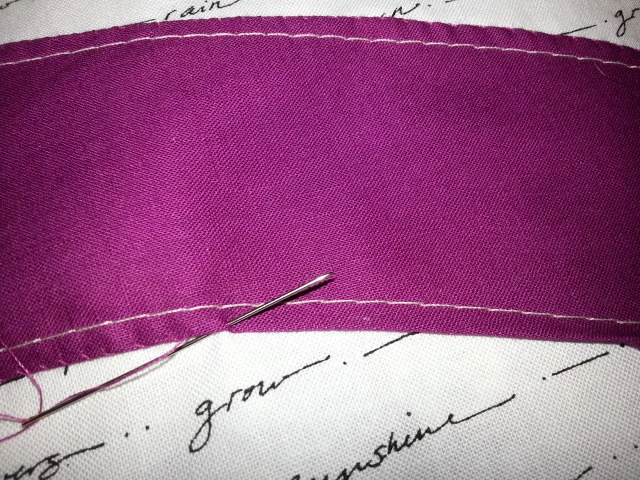 Detail of appliqué: White thread is the machine basting, the raw edge is turned under and the edge is being slip stitches
