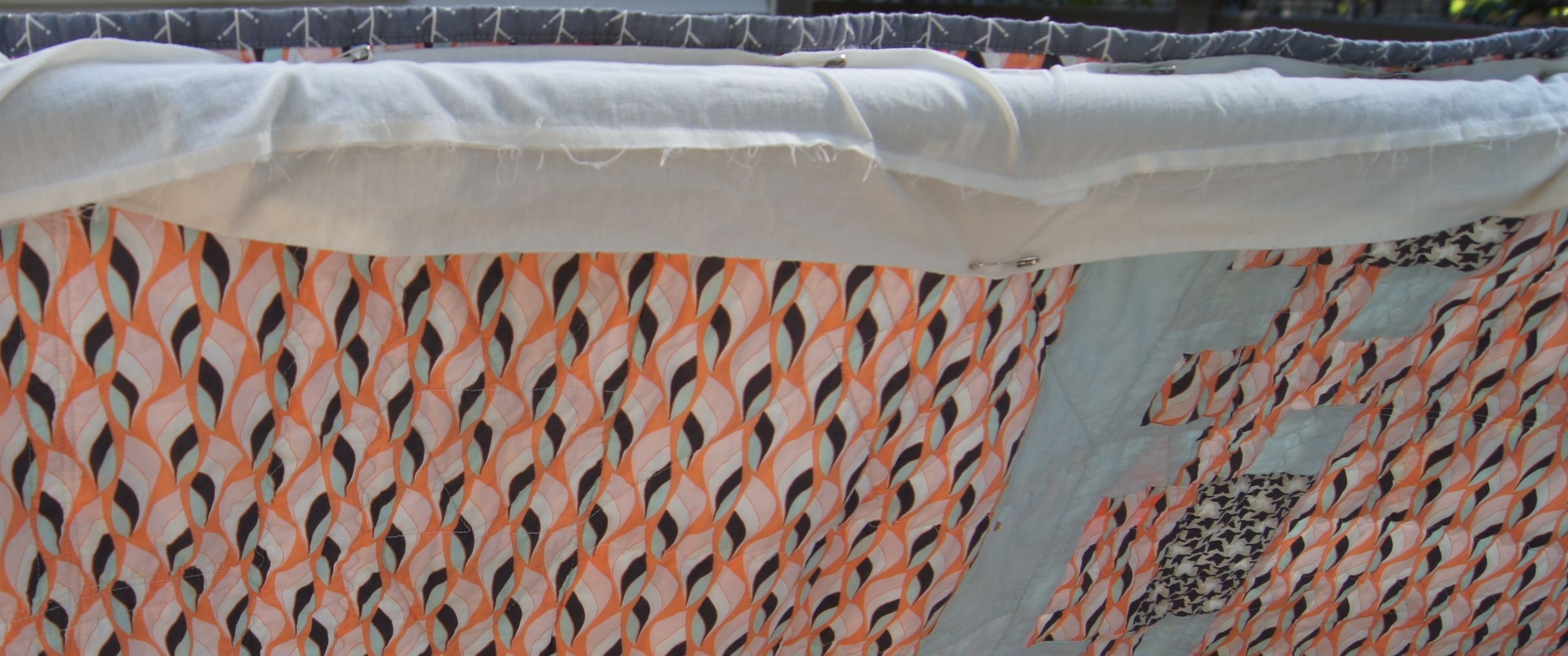 Back of the quilt with a sleeve pinned on and the bar of the frame inside the sleeve.