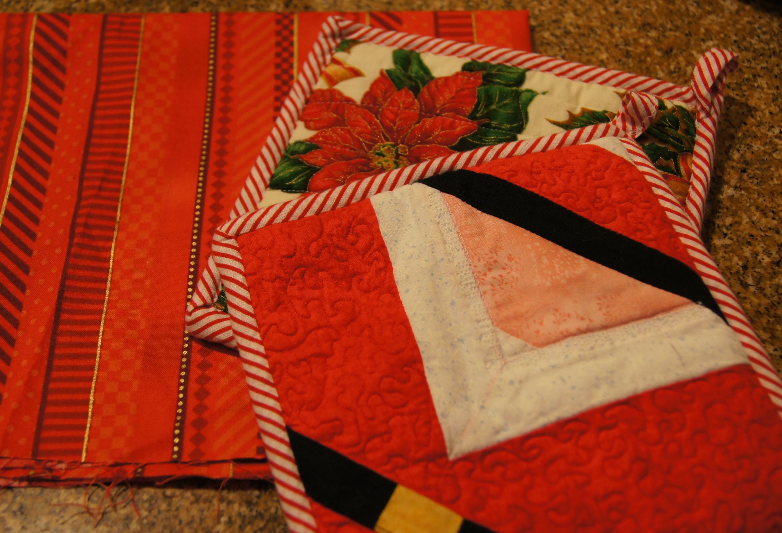 Quilted Santas on one side of the potholders, poinsettias on the flip side. Quilter--PBQ Guild member, identity unknown