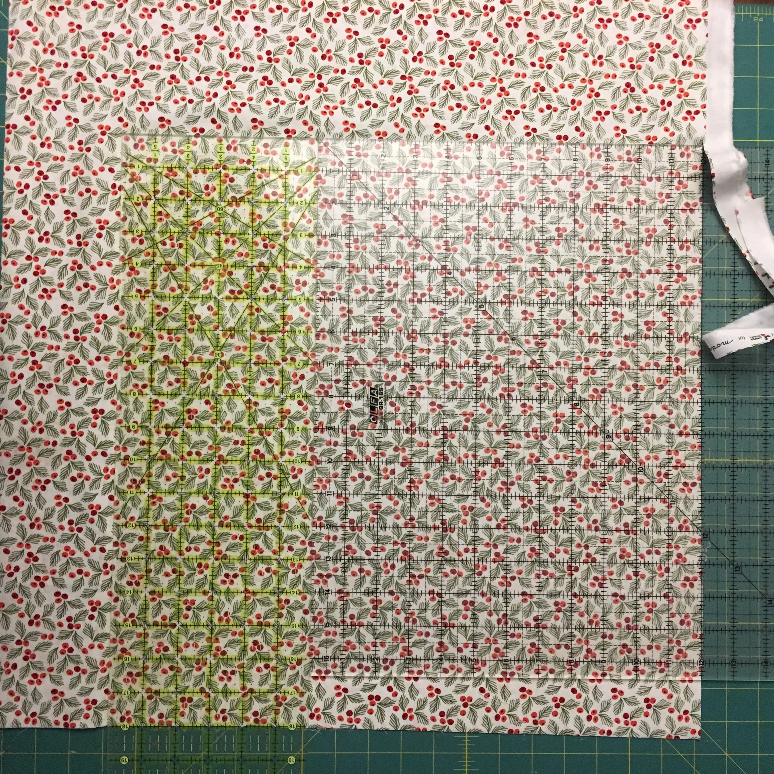 24 inch ruler is on the left, with the quilting square on the right. The fabric cut will be 18 inches long and 18 inches wide. Note the fabric at the lower right edge that isn't covered by the shorter square ruler. That's fine because no cut is needed there.