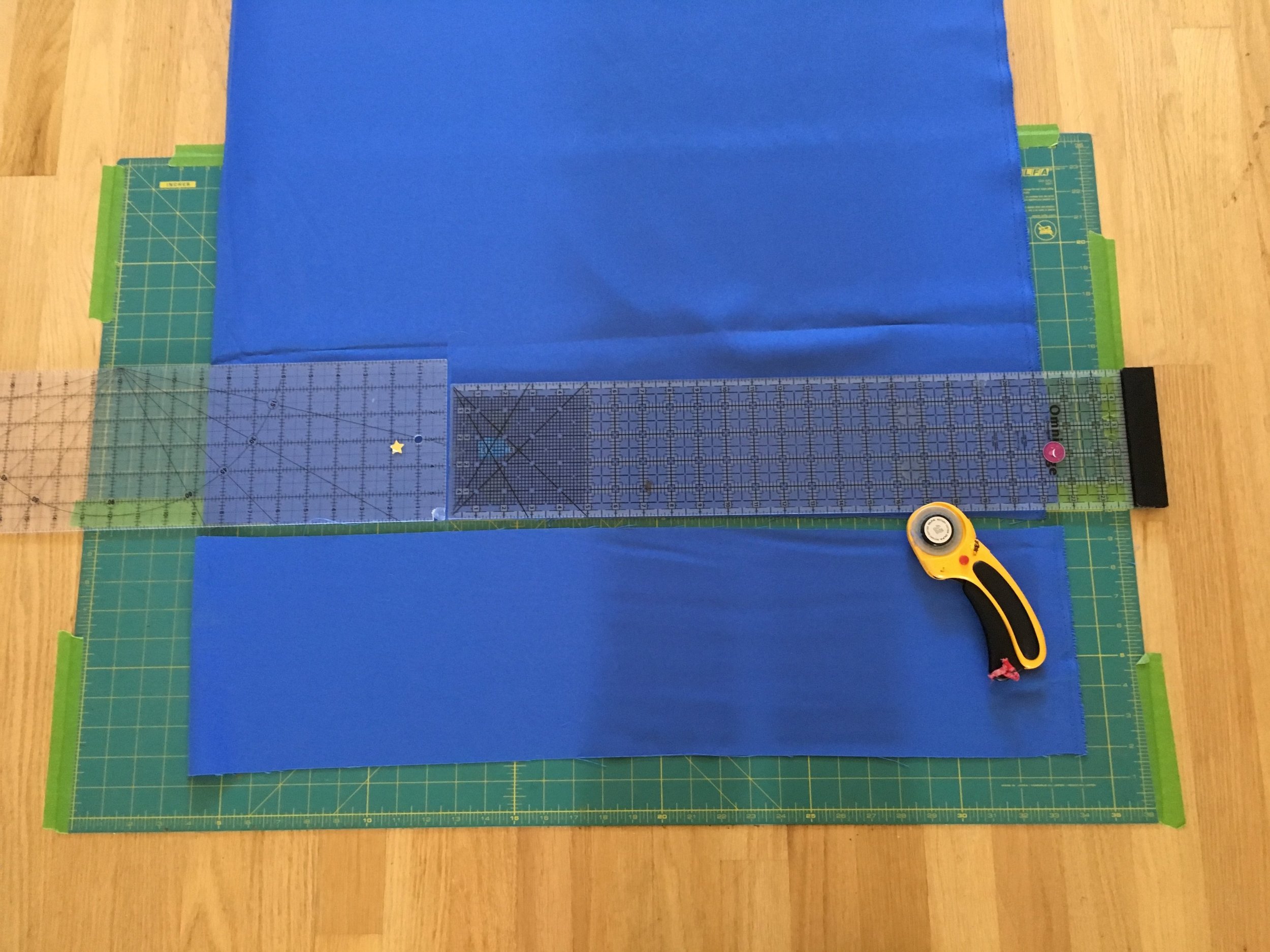 Cutting mat taped to the floor with rulers and rotary blade
