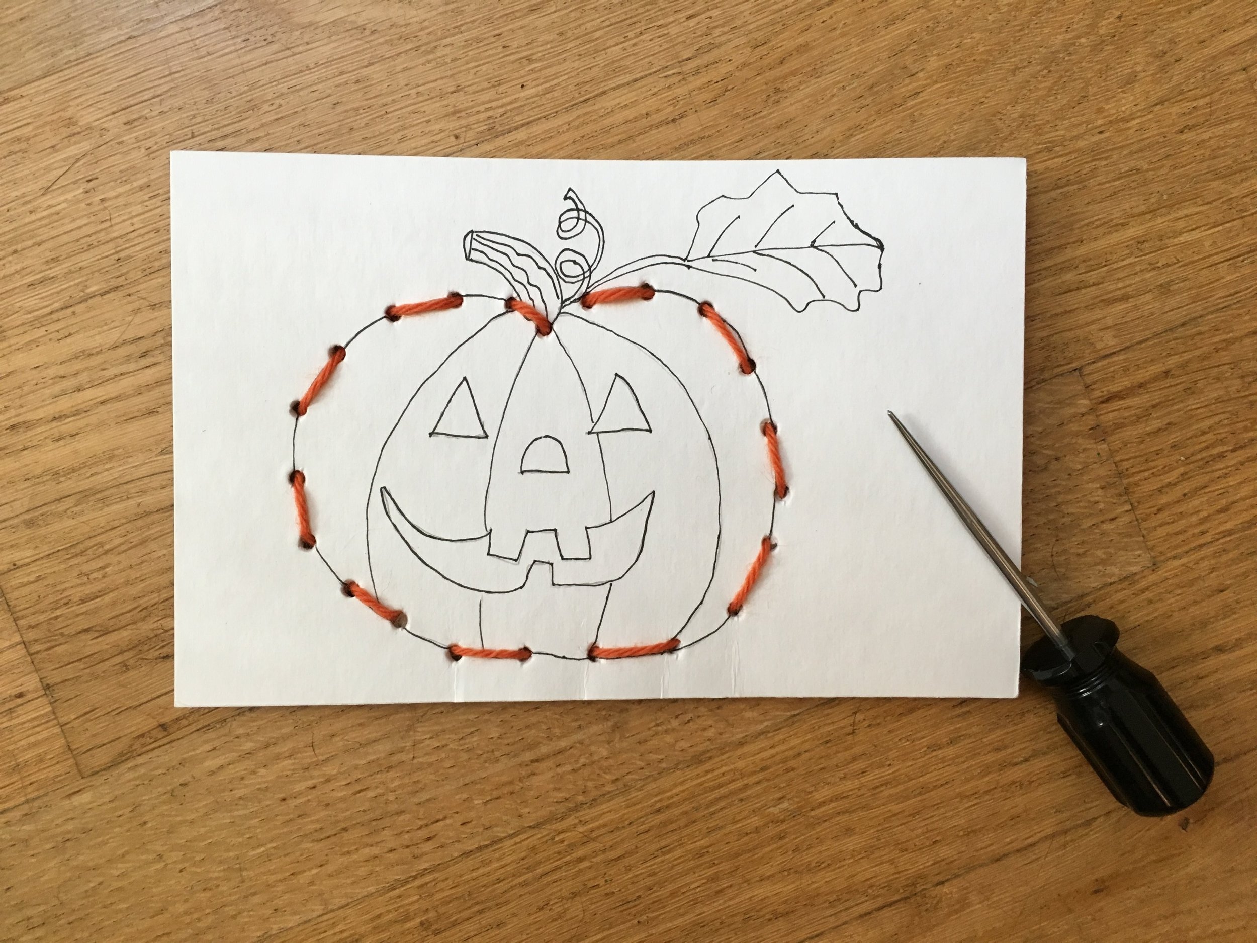 Completed sewing card and with awl used to punch the holes