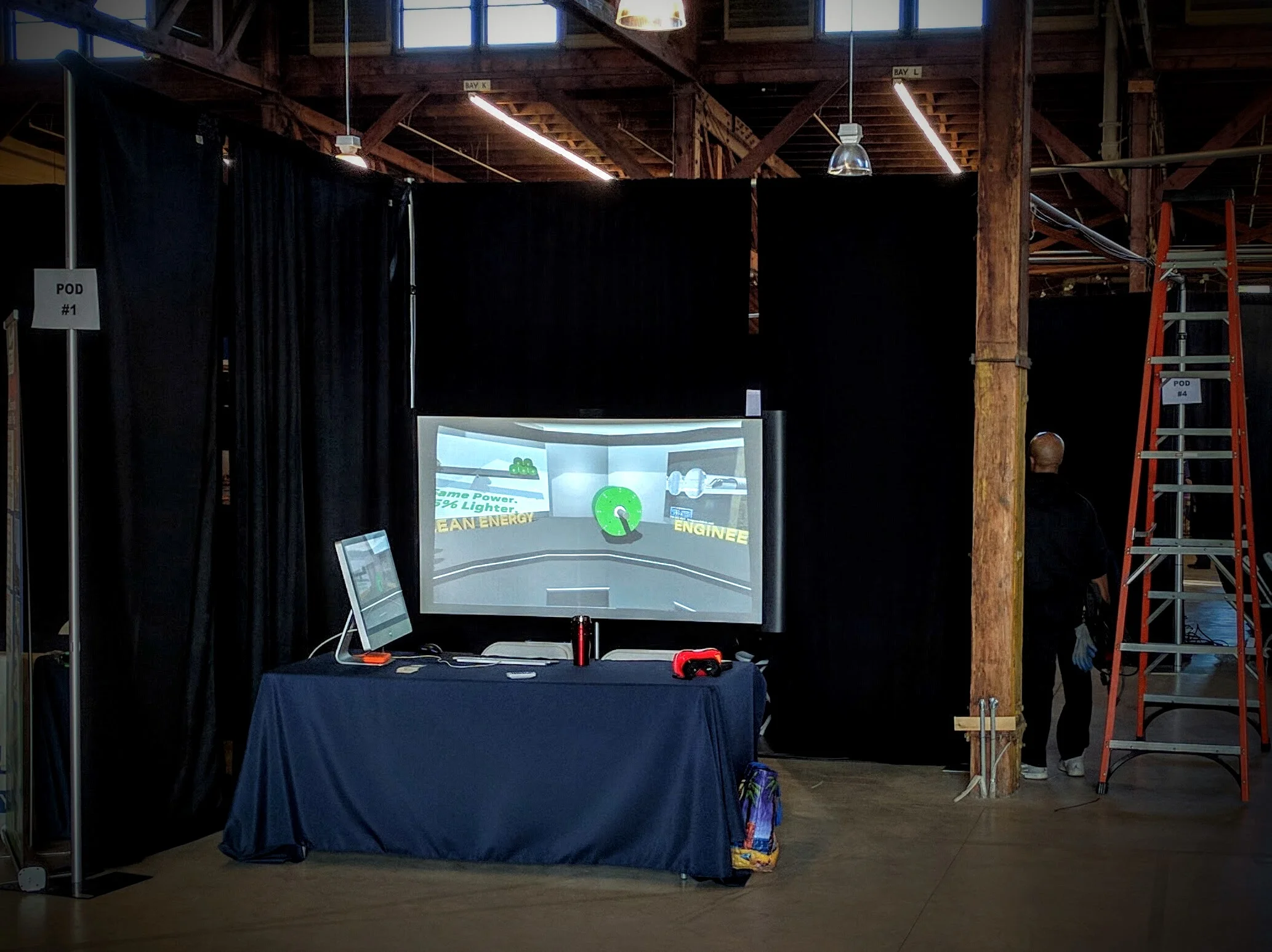 From left to right: 27" iMac (my travel computer), interactive presentation on the projector screen, red coffee thermos (mandatory), VR goggles, Trader Joe's bag with snacks, man with orange ladder.