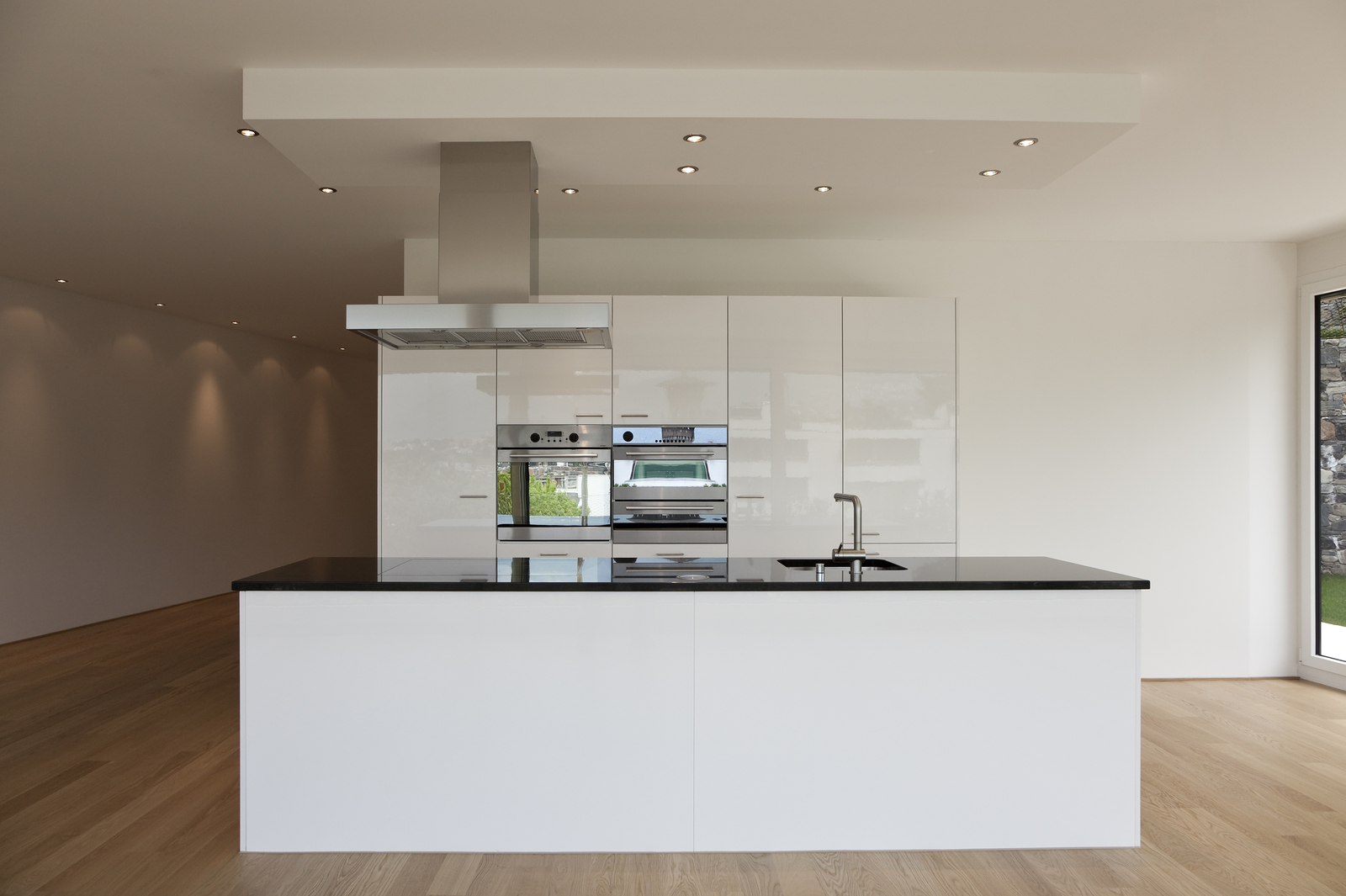 Condo Kitchen - Combination of lacquered and low sheen cabinetry, built-in fridge and ovens, polished chrome plumbing fixtures and appliances, built-in cooktop flush in solid black engineered stone countertop. White oiled 5" wide oak plank floor. Polished chrome cabinet handles. 