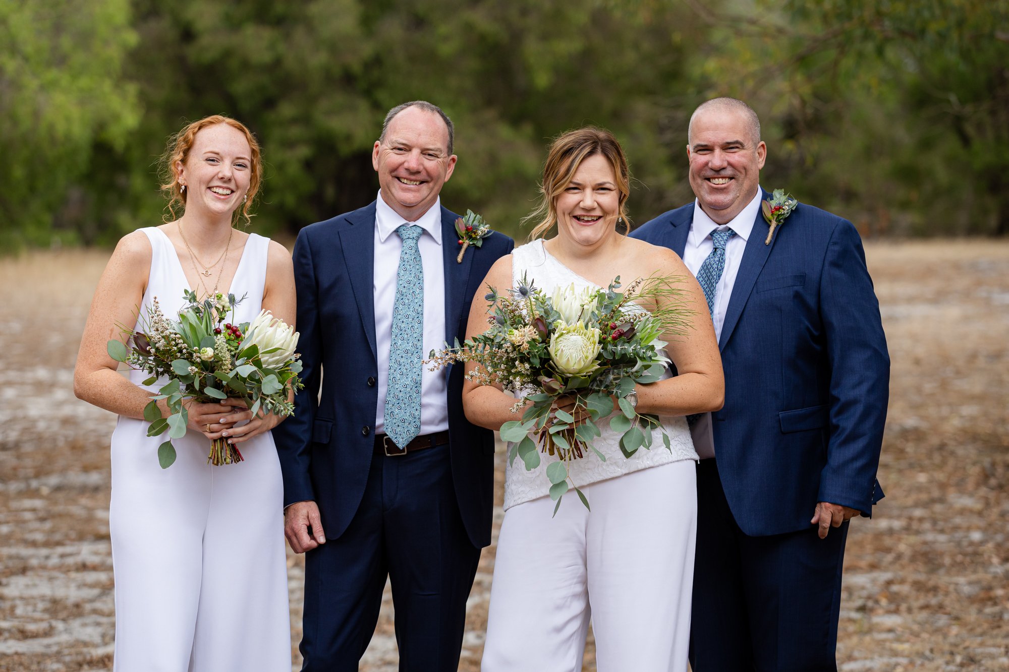 Two guys and two ladies in wedding photo holding a bouquet