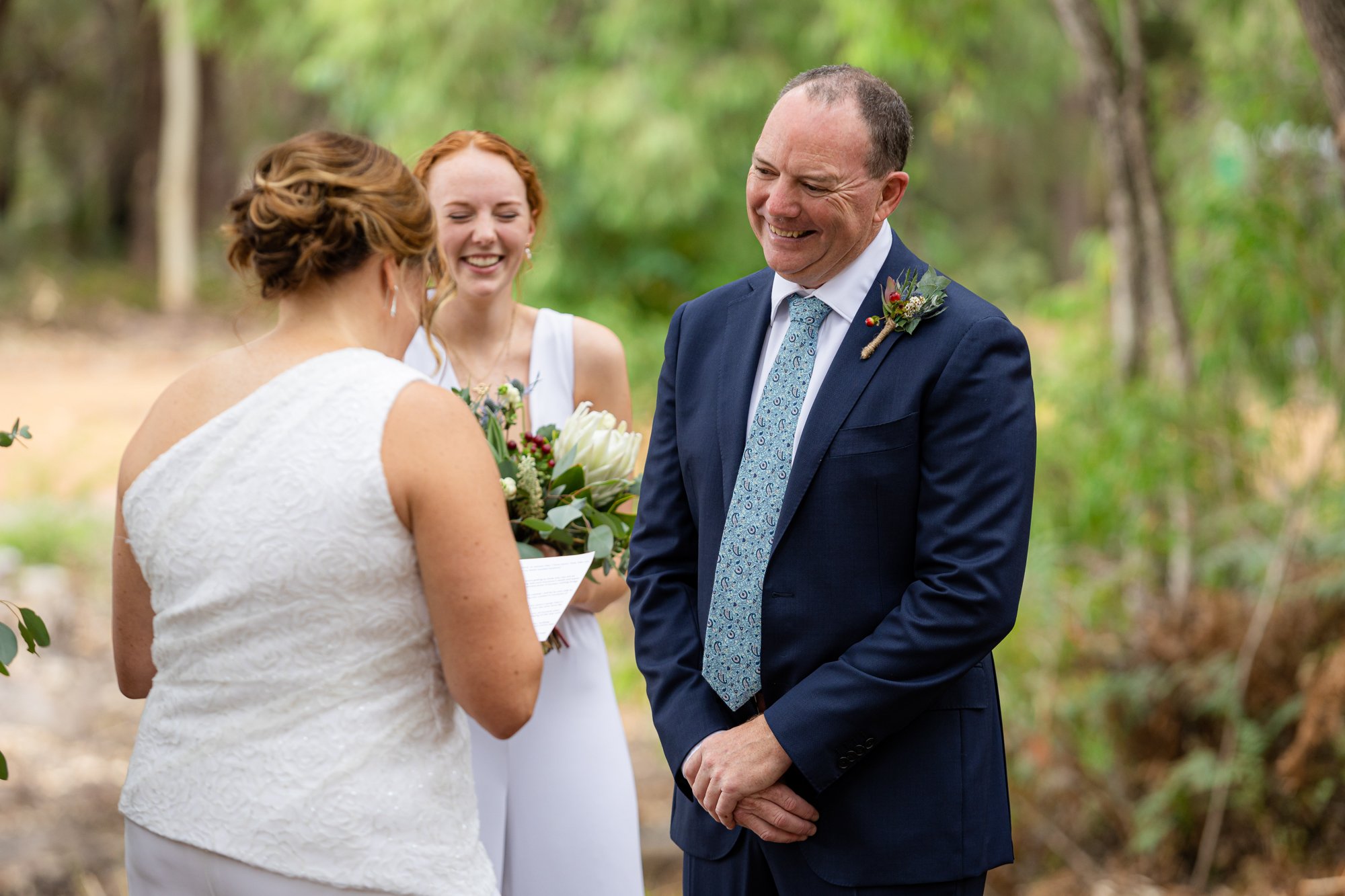 groom smiling as his bride say her vows