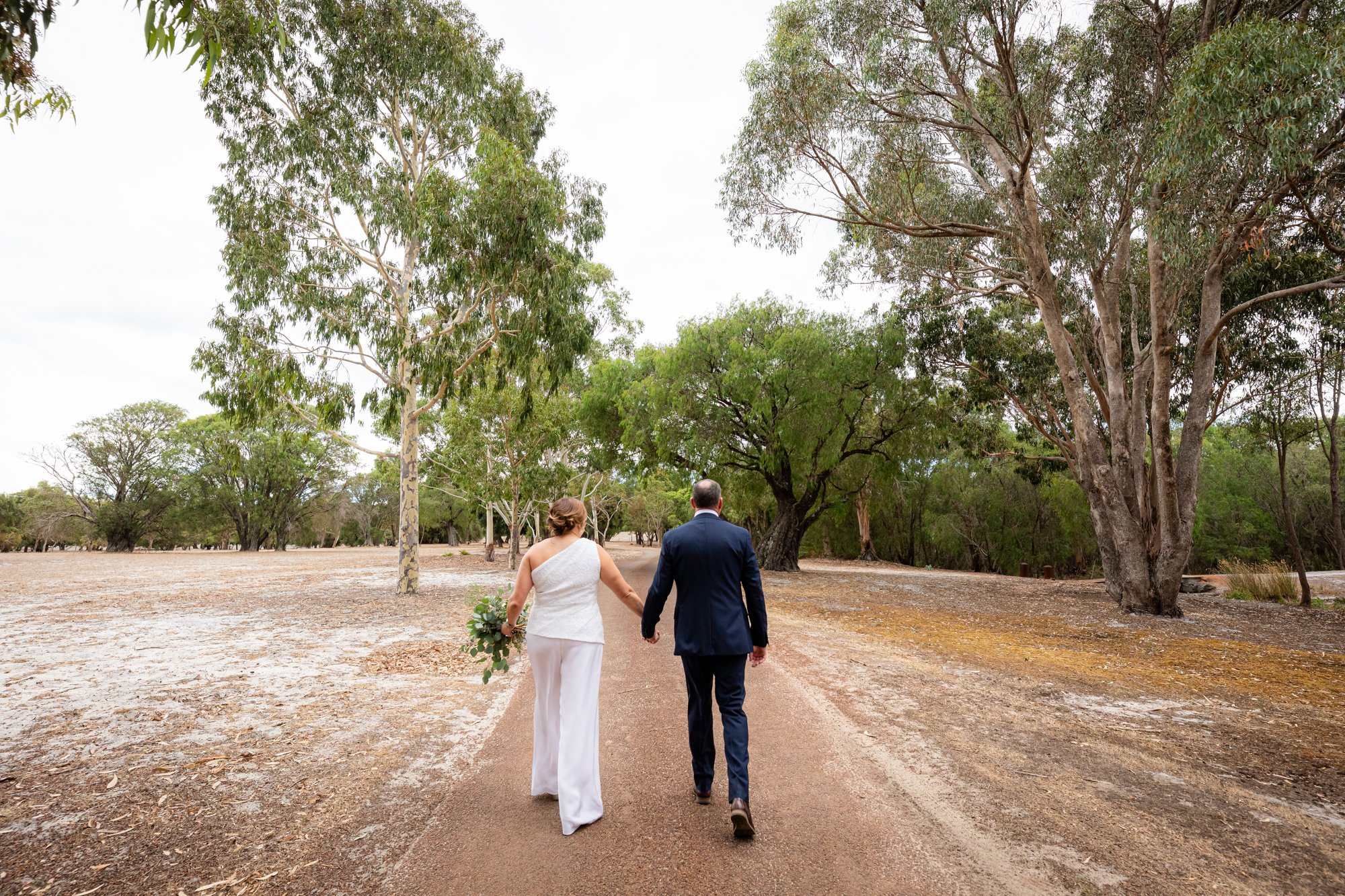Bride and Groom walking by the trees pictorial