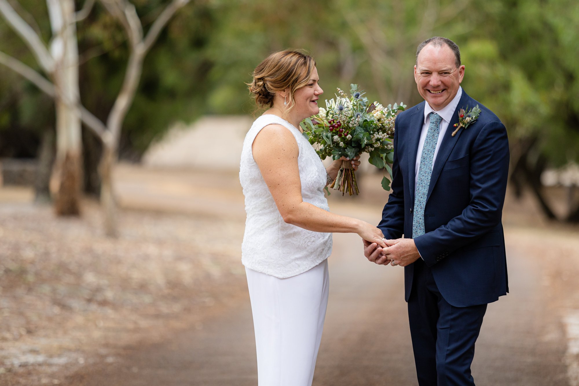 bride holding a bouquet of flowers smiling with groom