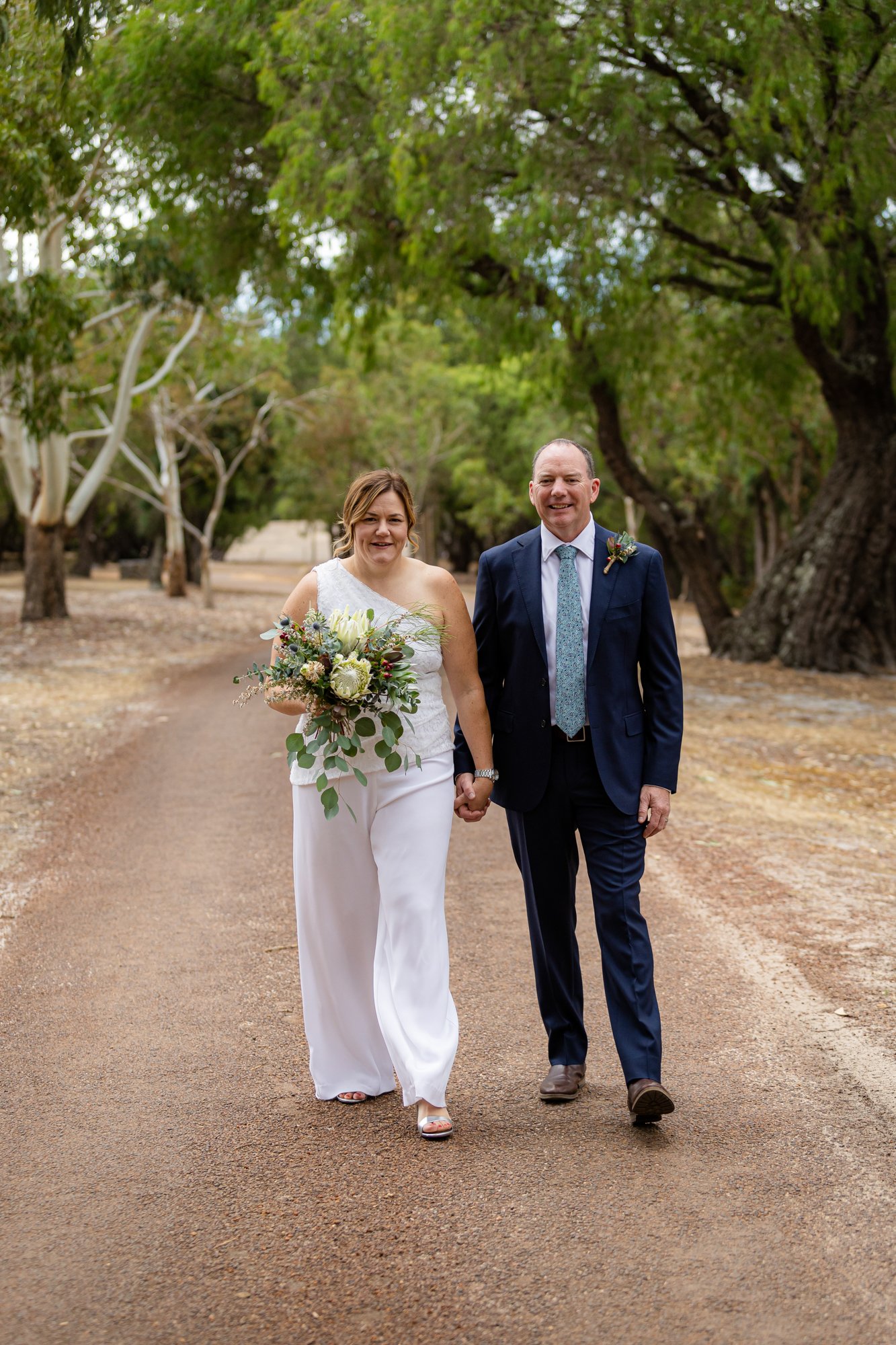 walking bride and groom while bride holds a white bouquet