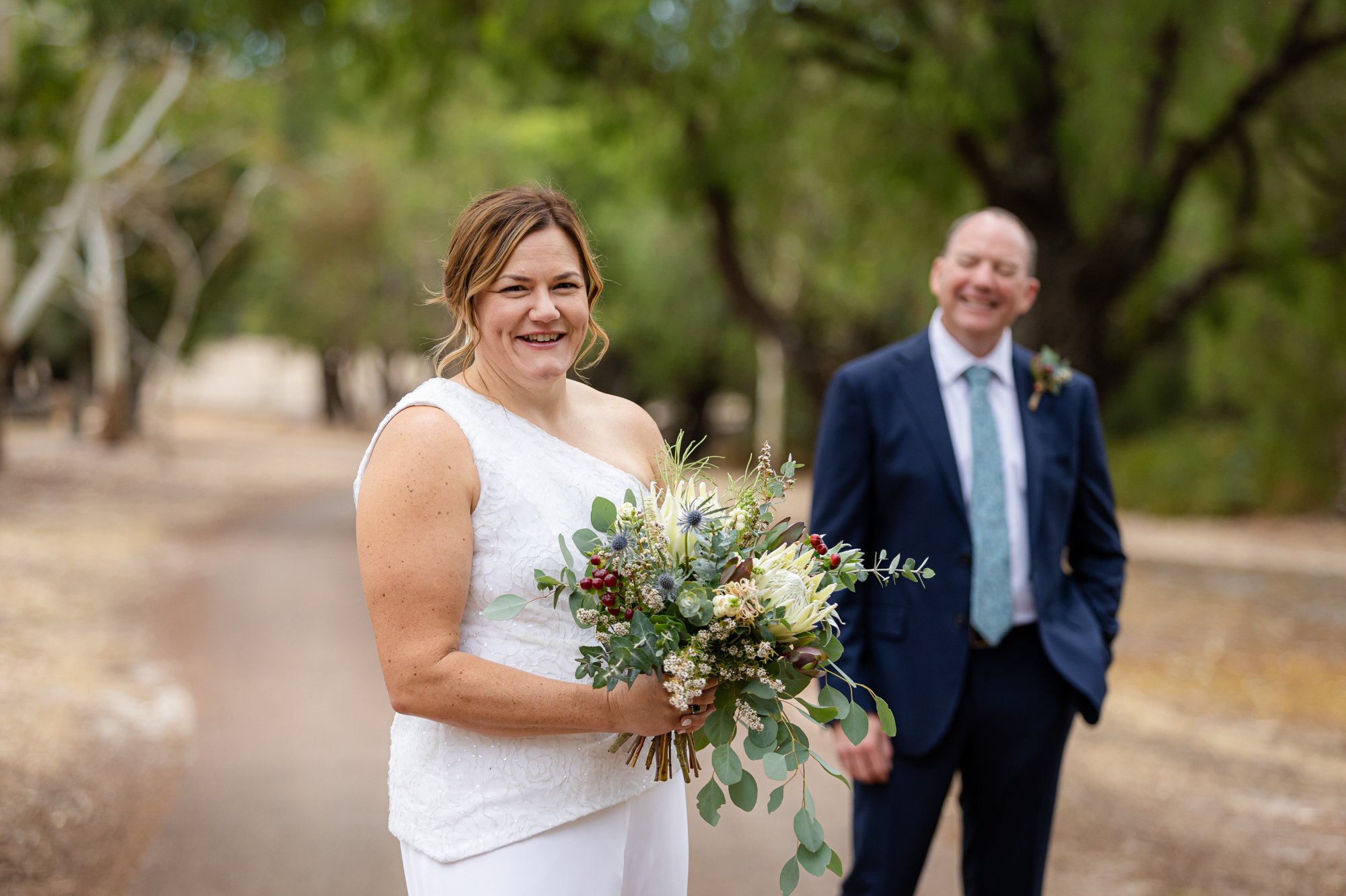 bride holding bouquet while husband looks at her smiling