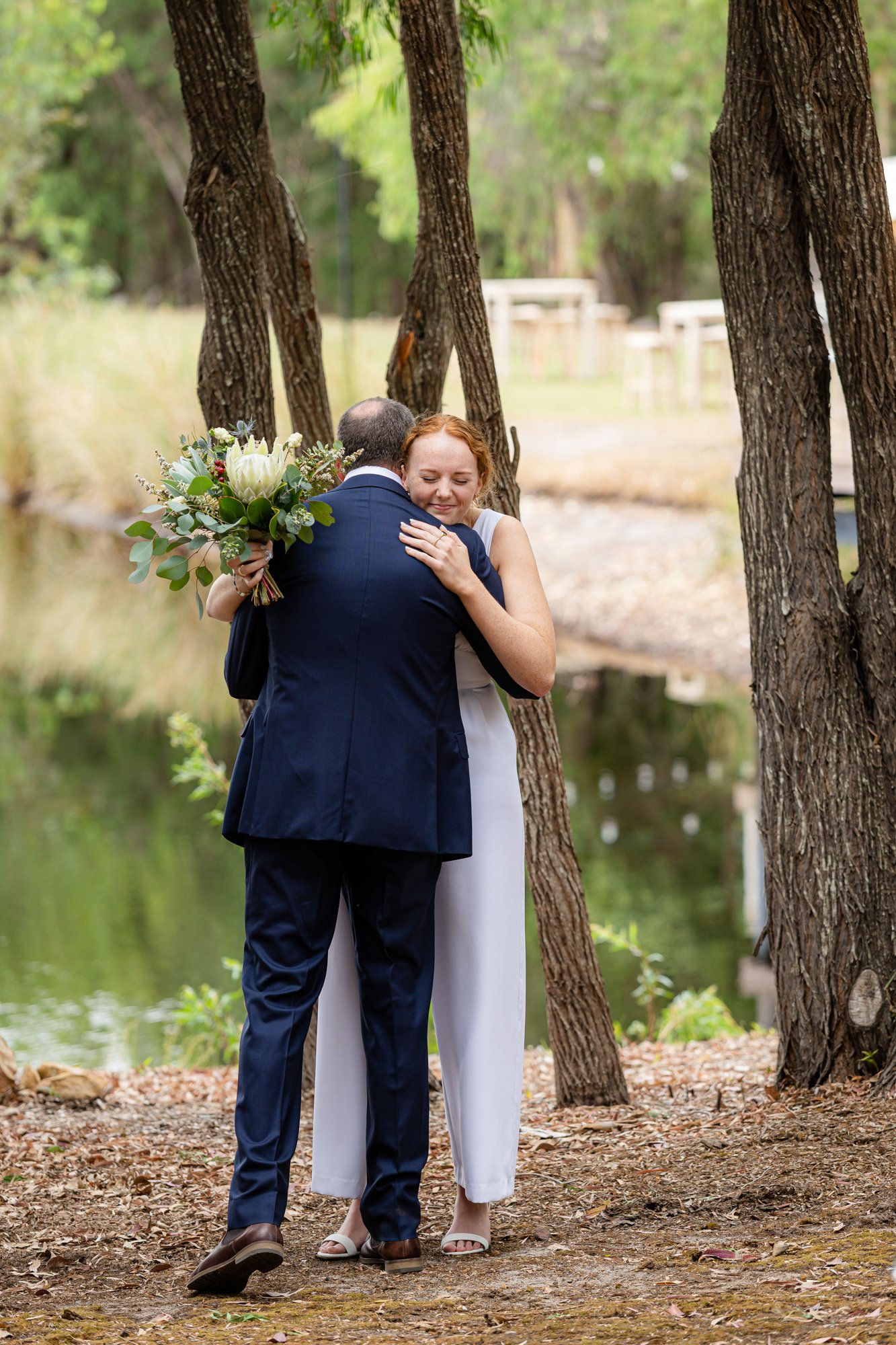 lady holding white bouquet while hugging a man