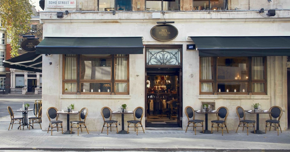 Six Storeys exterior, tables with two chairs outside under the awnings