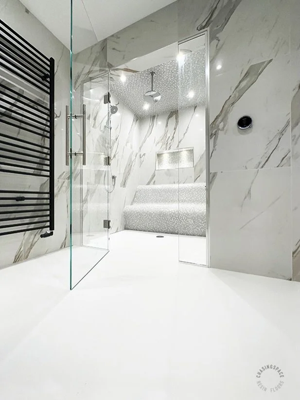 Our seamless flooring adds a contemporary finish to luxury wet rooms and bathrooms. 

In the first wet room image, white resin flooring creates a smooth transition that elegantly leads to a distinctive shower and seating area. 
 
In the second image,