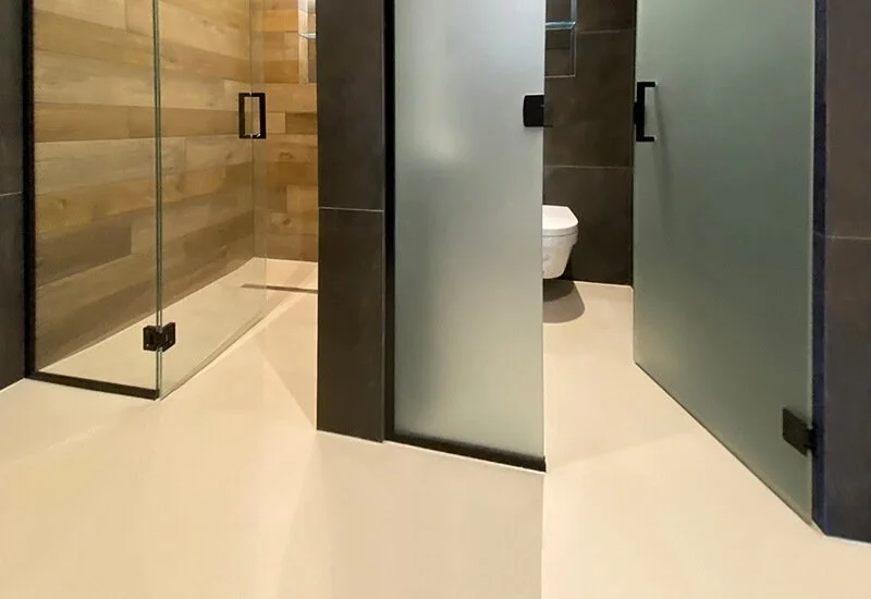 A stylish wet room with a durable resin floor that extends into the walk-in shower area for a clean, cohesive look.