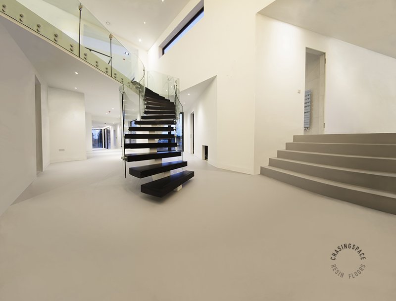 Bright, open-concept living space featuring smooth resin flooring and wide concrete steps.