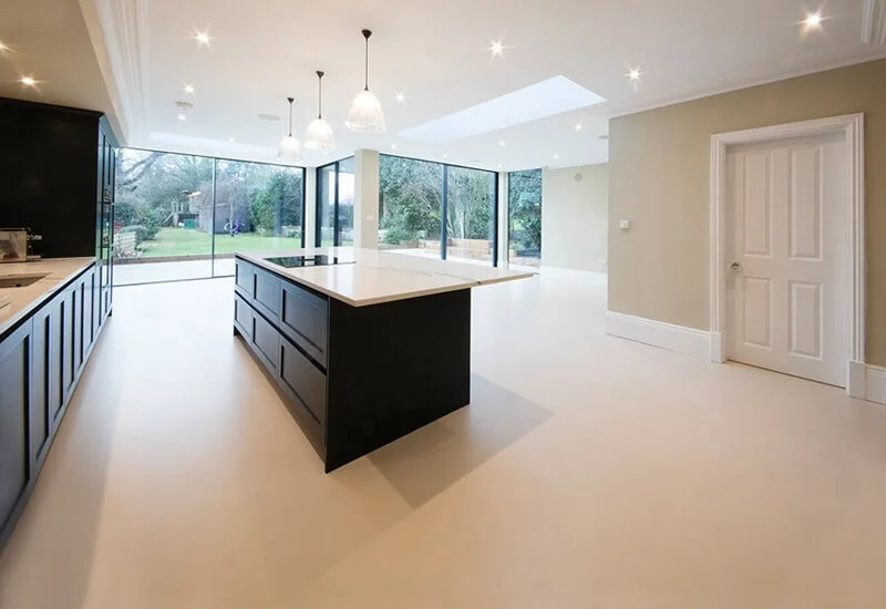 A bright, modern kitchen featuring a smooth, seamless resin floor that extends throughout the open-plan space.