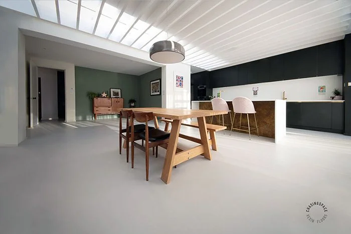 Open-plan living area defined by a smooth, light grey poured resin floor.