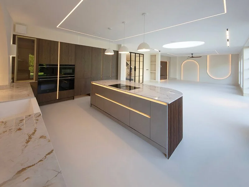 Modern open-concept kitchen and living area with marble countertops, wooden cabinetry, and minimal lighting fixtures.