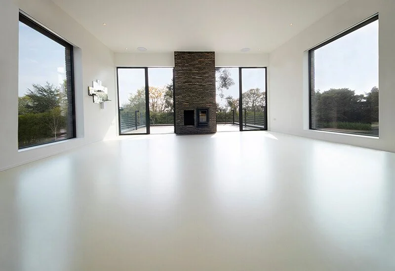 A contemporary living area with a clean grey resin floor and a striking stone-clad fireplace.
