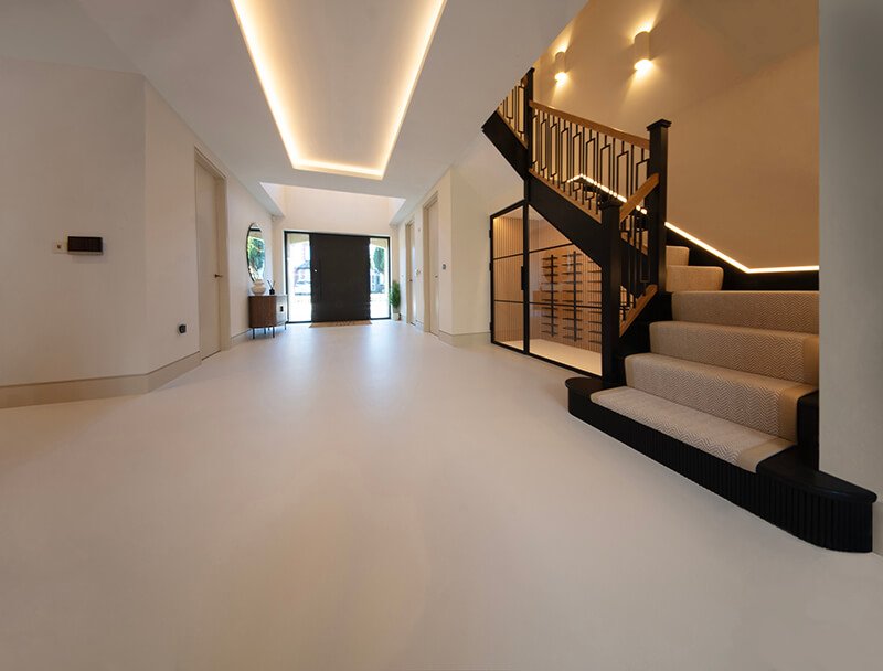 Minimalist resin floor in a residential hallway with a modern staircase.