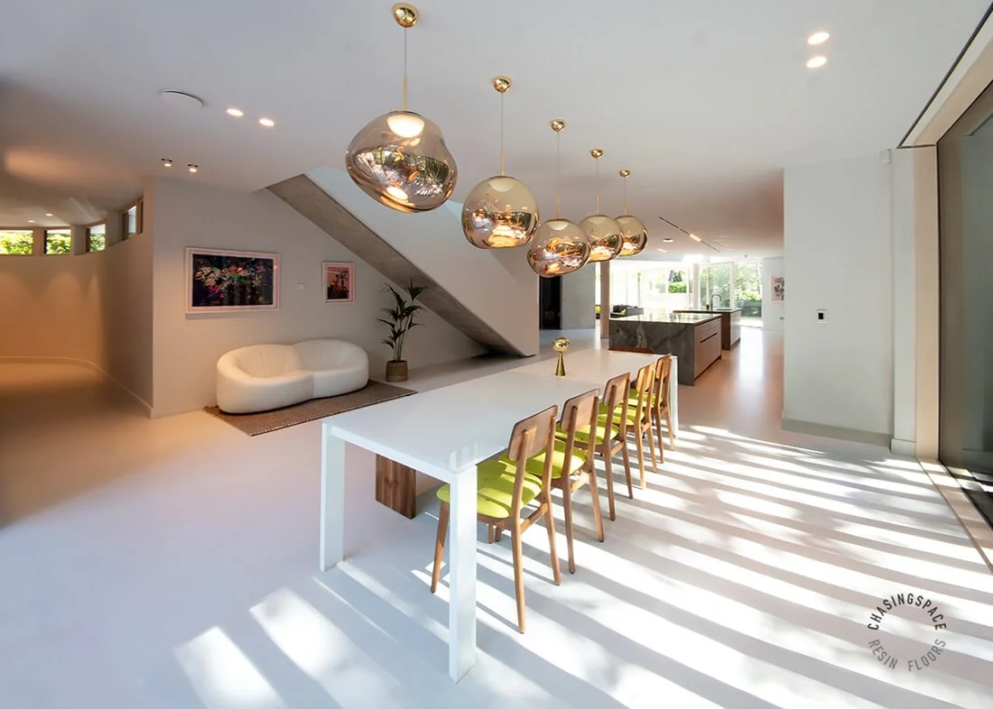 Seamless light grey resin flooring provides a sleek foundation for a sunlit living space.