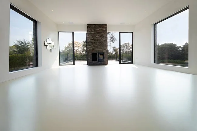 A seamless expanse of satin-finish resin flooring, reflecting the surrounding light and space.