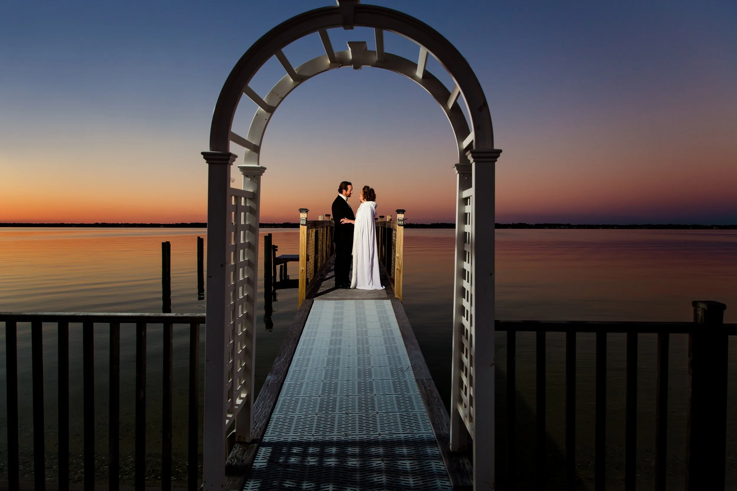 Bride and groom standing under an arbor on a dock near nNavarre Beach Florida taken by a Jacksonville Florida, St. Augustine photographer