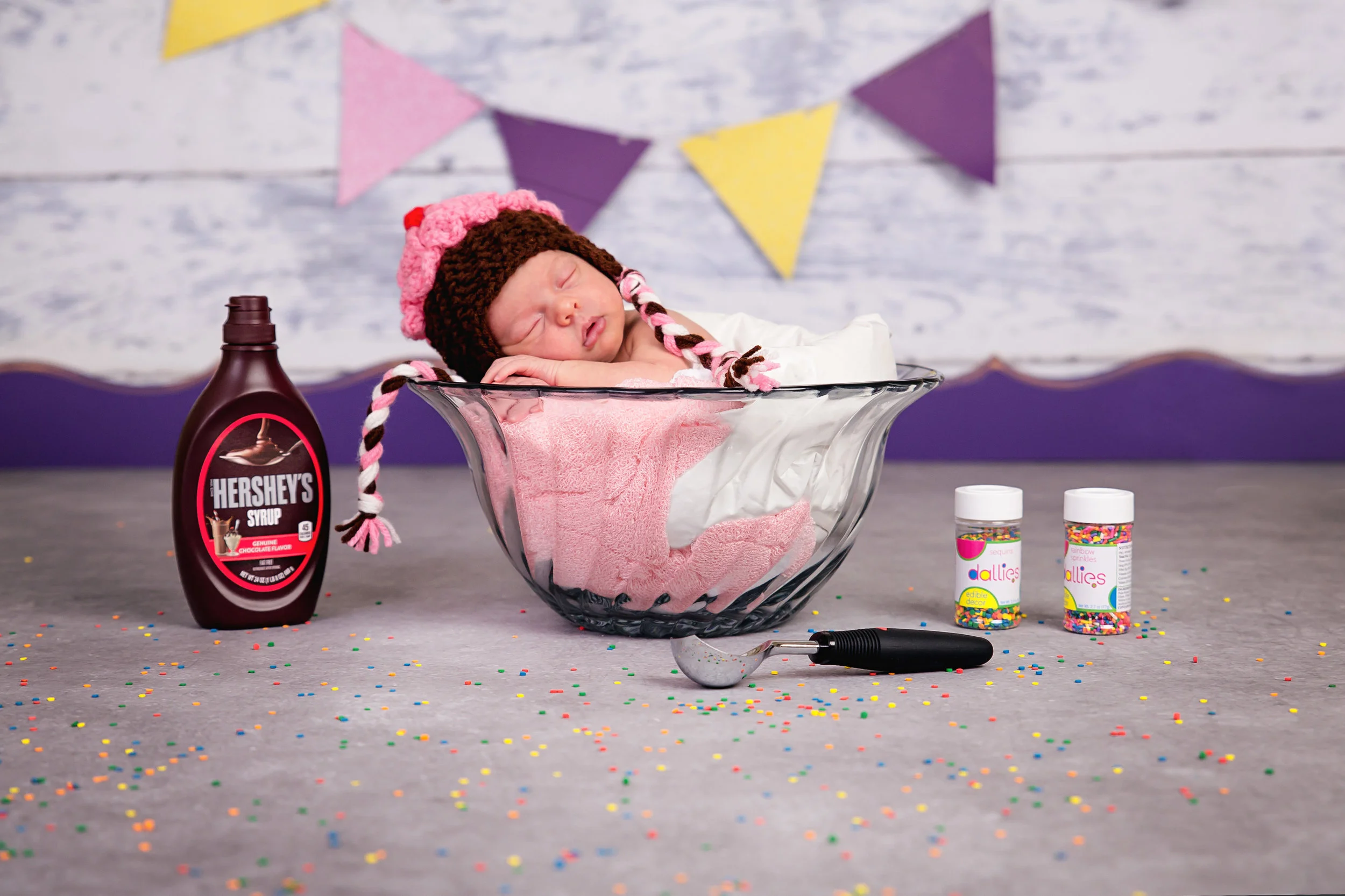 Creative newborn portrait of a sleeping baby in a playful ice cream sundae themed photography setup.