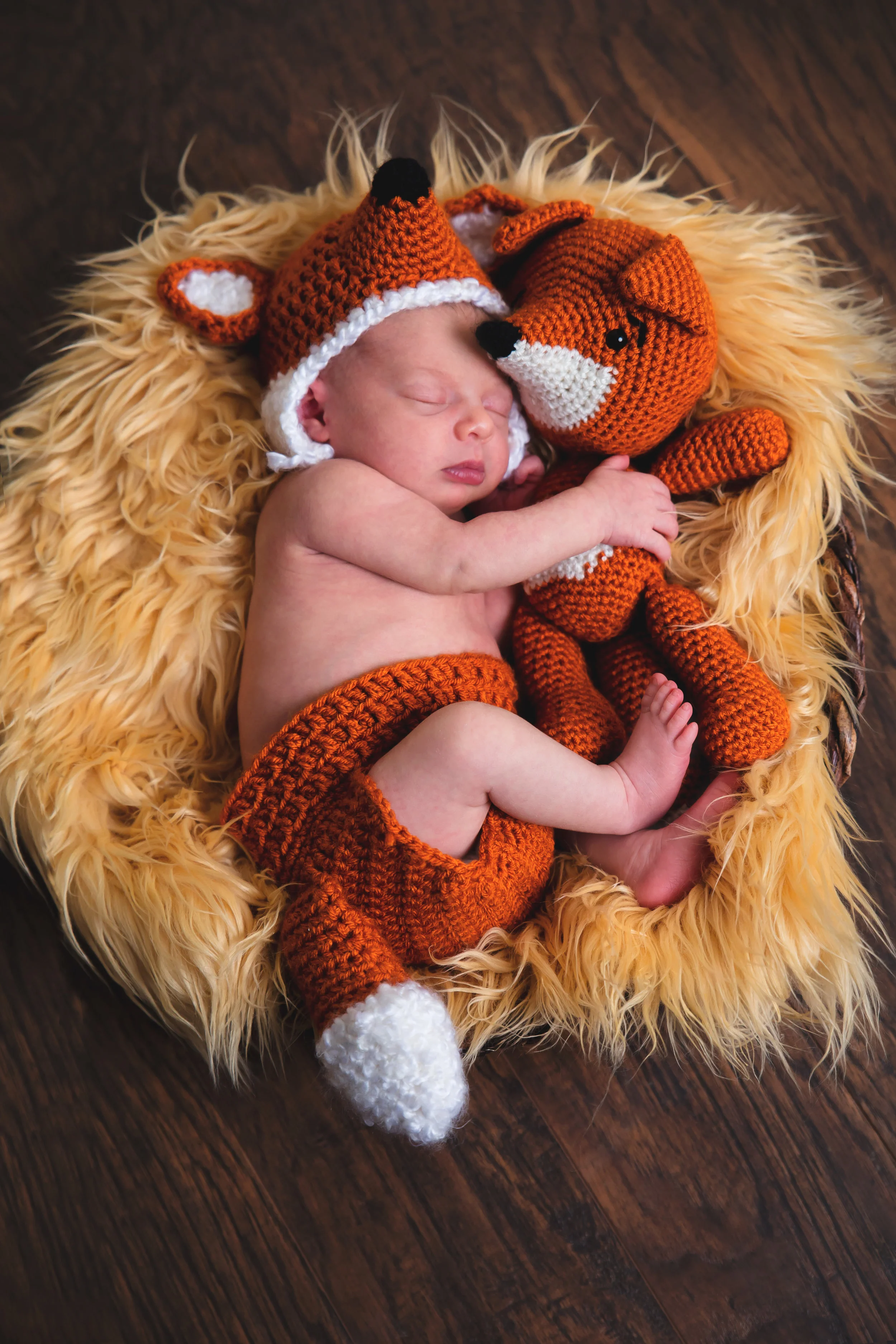 Sleeping newborn baby wearing a fox hat and cuddling a fox during a creative newborn photography session in Navarre, Florida.
