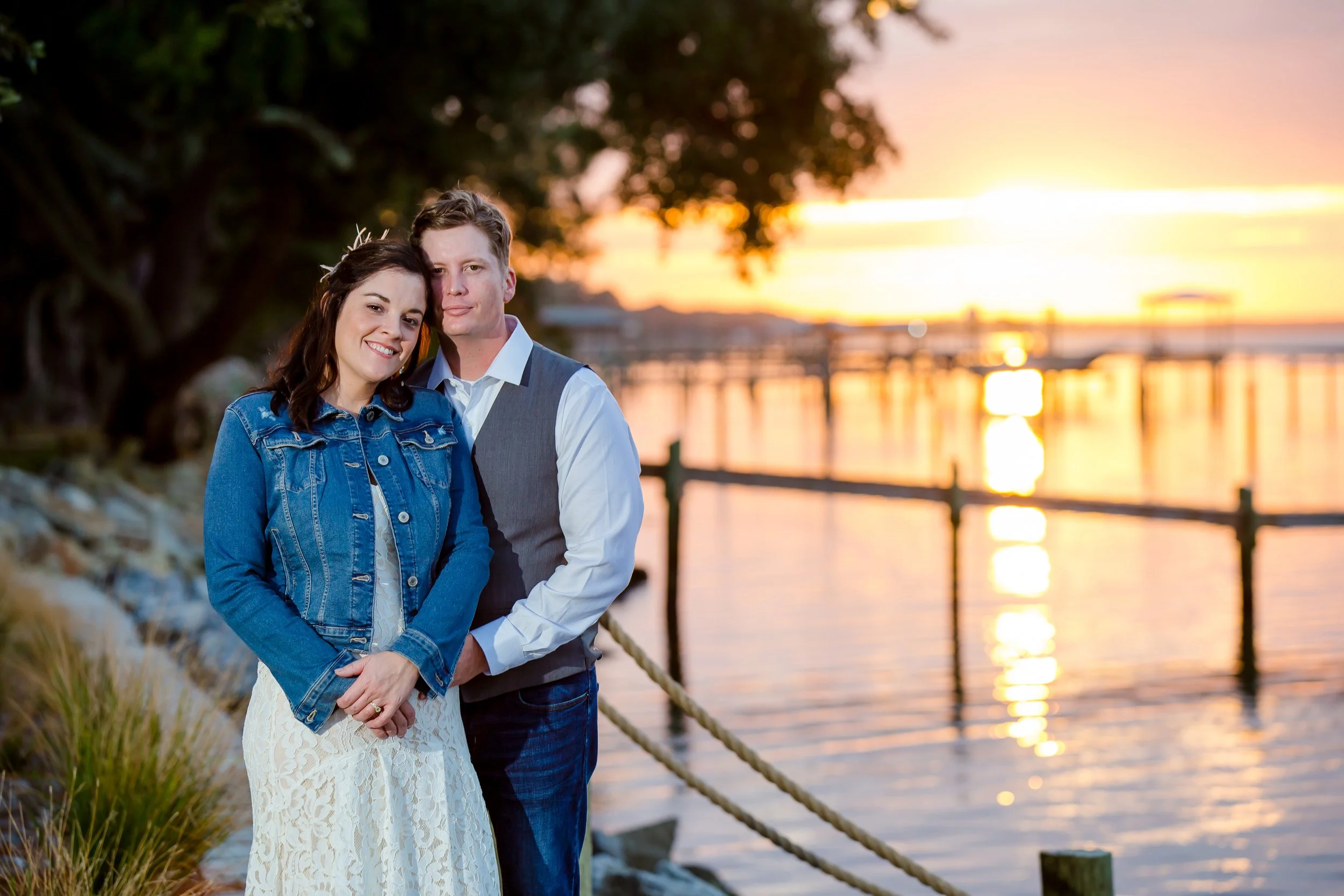 Bride and groom standing together with a beautiful lit sunset at the bay waters behind them photographed by a Jacksonville Florida St.Augustine wedding photographer