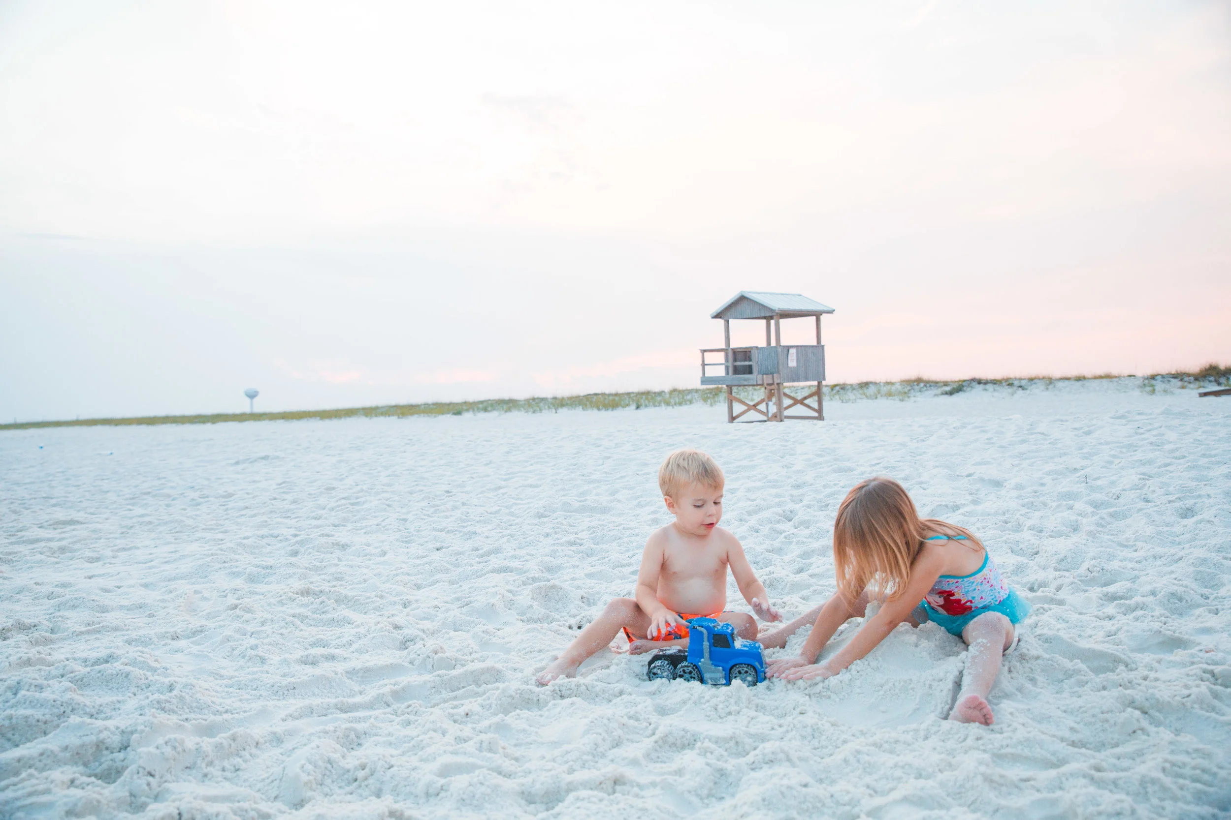Children playing in the white sand at the beach during golden hour for candid family photography