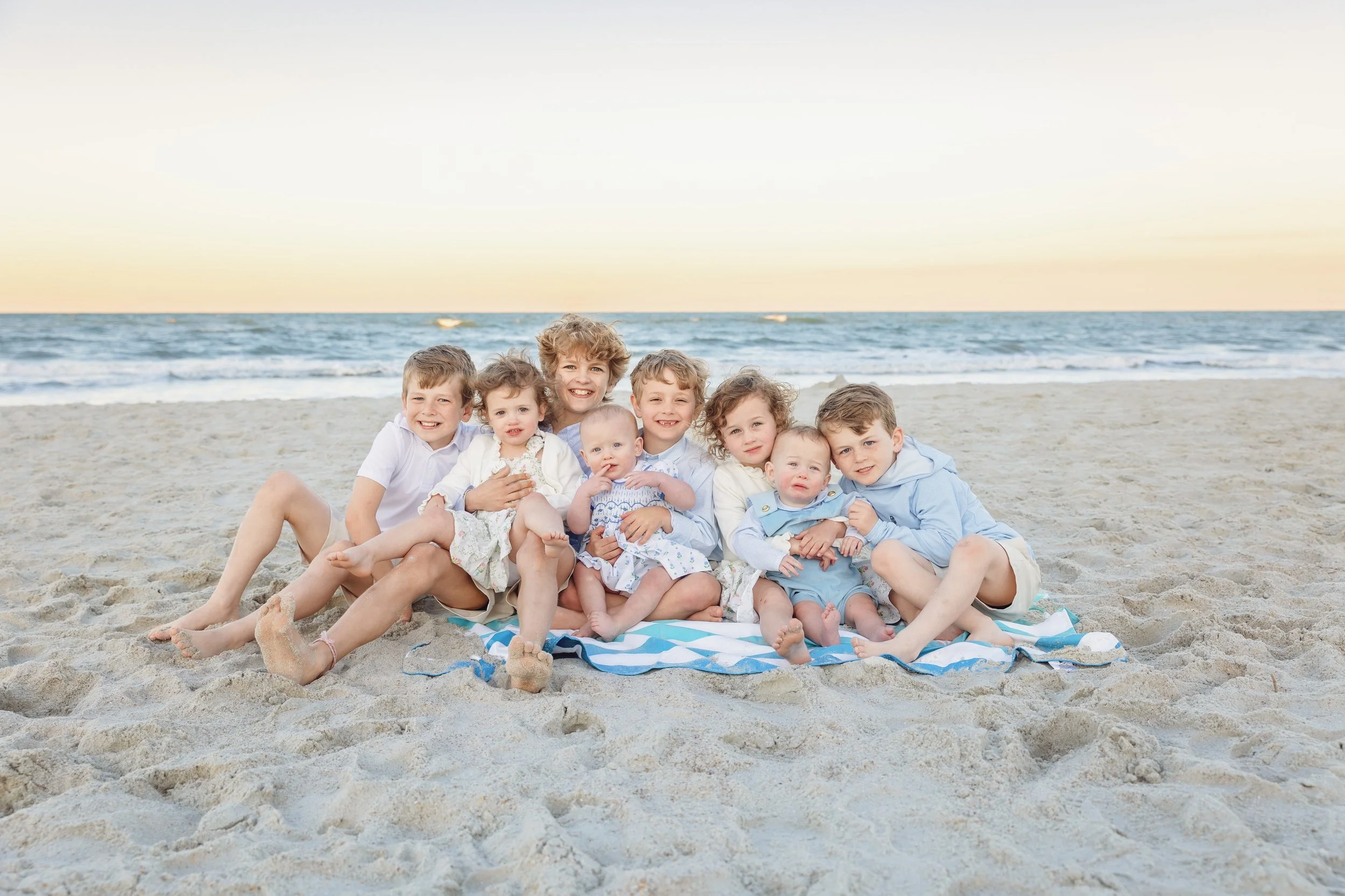 Children's beach photography featuring two young girls sitting together on the white sand at sunset