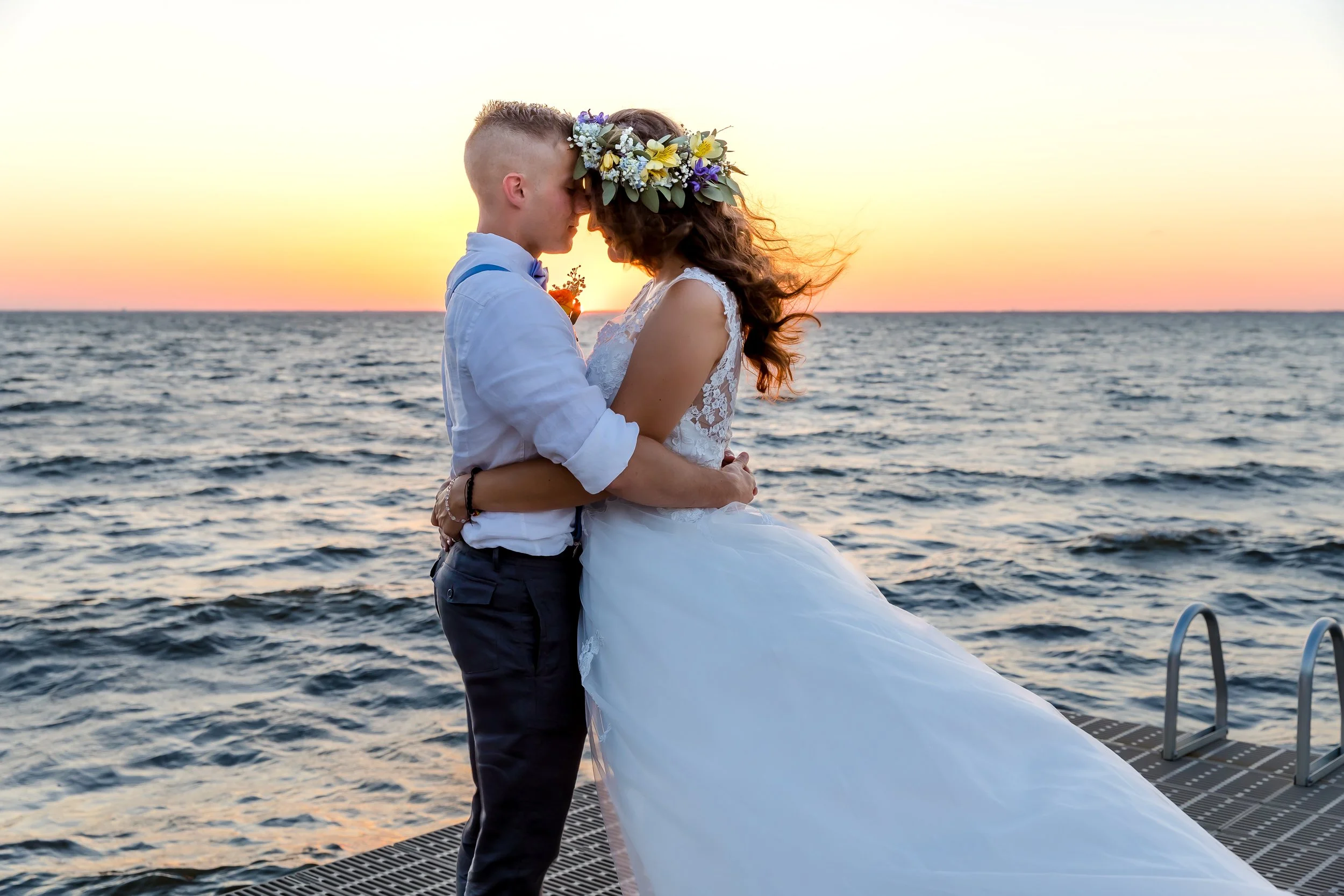 Bride and groom walking on a dock towards a sun set lit sky photo taken by St. Augustine and Jacksonville beach photographer