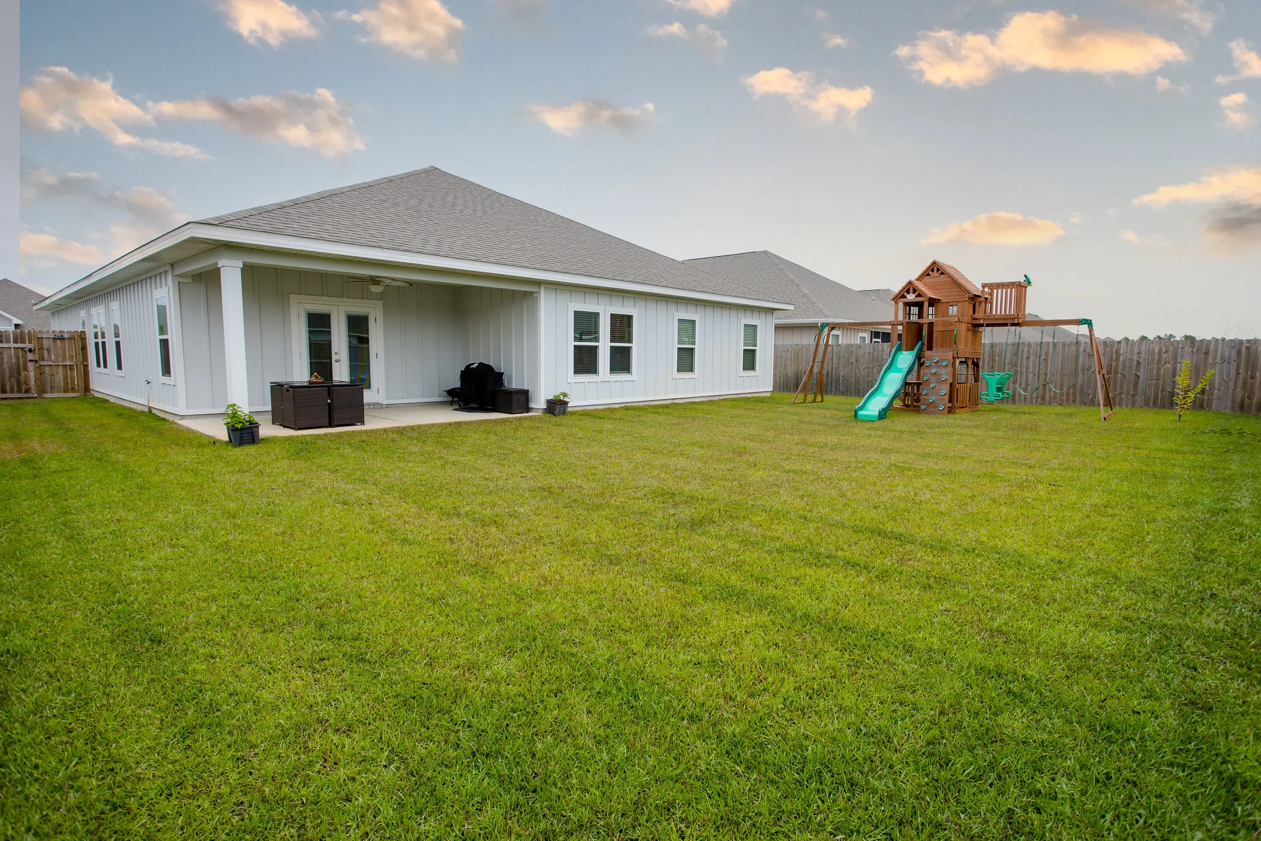 Real estate photography showing a spacious backyard, covered patio and exterior of a Florida home