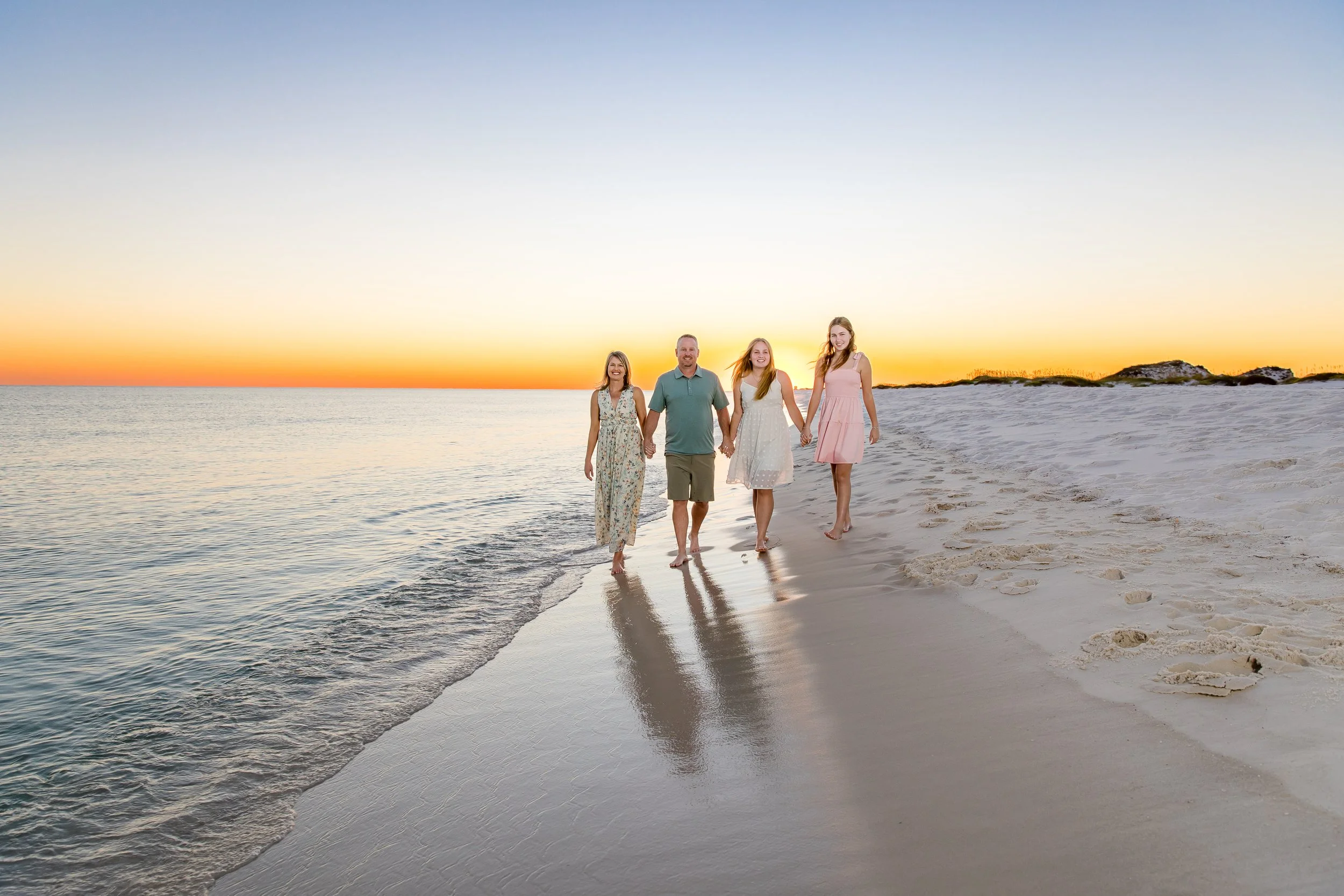 Family walking along the shoreline at sunset during a Navarre Beach family photography session by Inspired By You Photography.