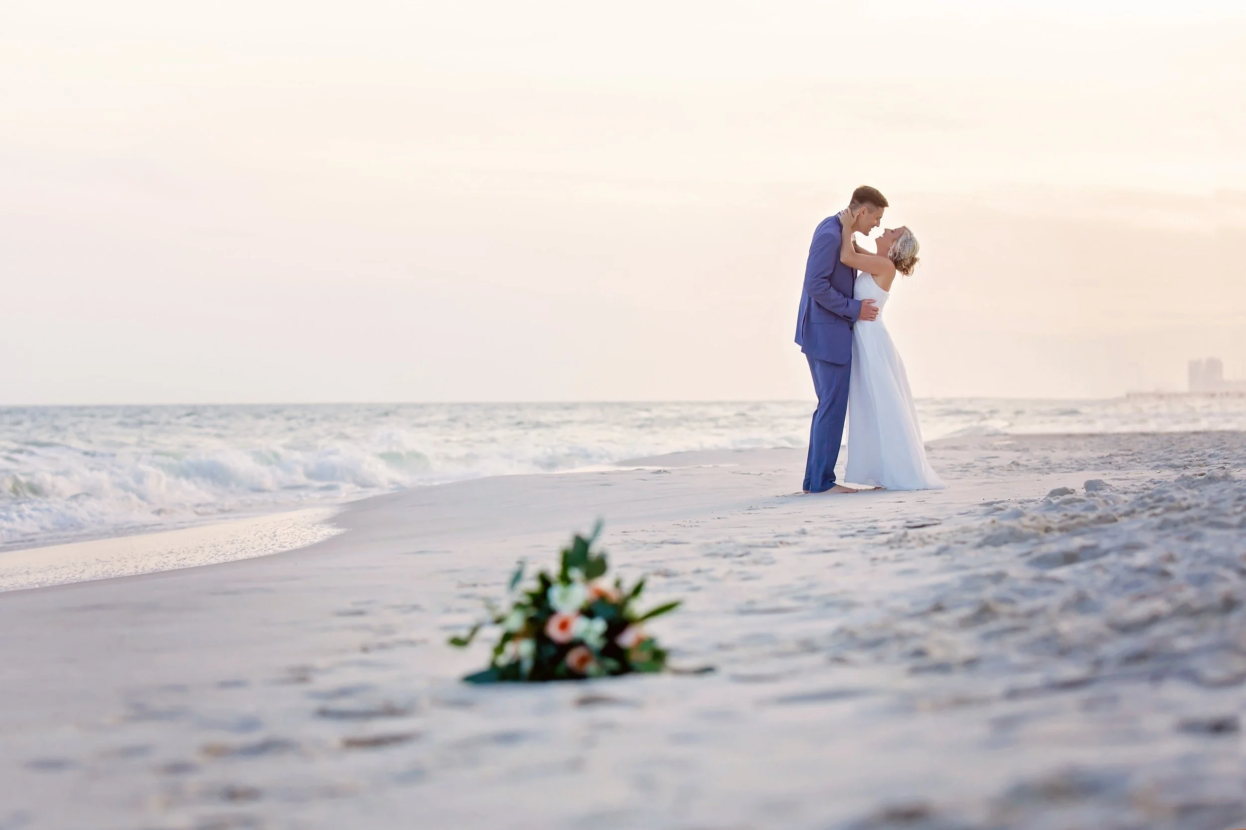 a picturesque moment of the Bride and Groom embracing each other  on the white beaches of Orange beach alabama