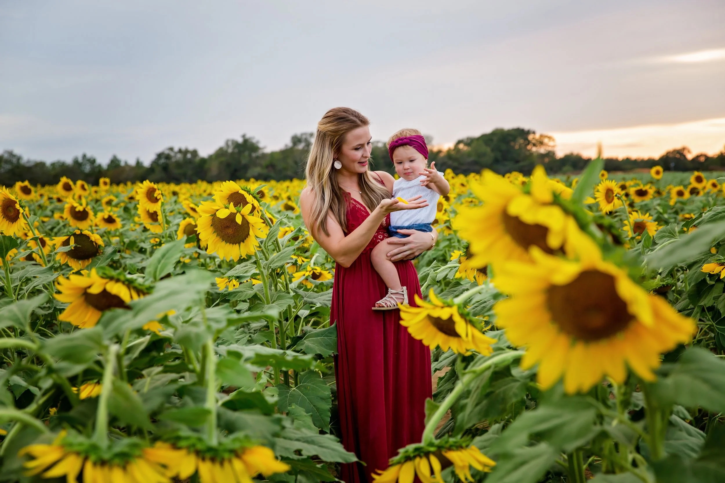 A picture of a mother holding her daughter in the middle of a sunflower field in Jacksonville Florida