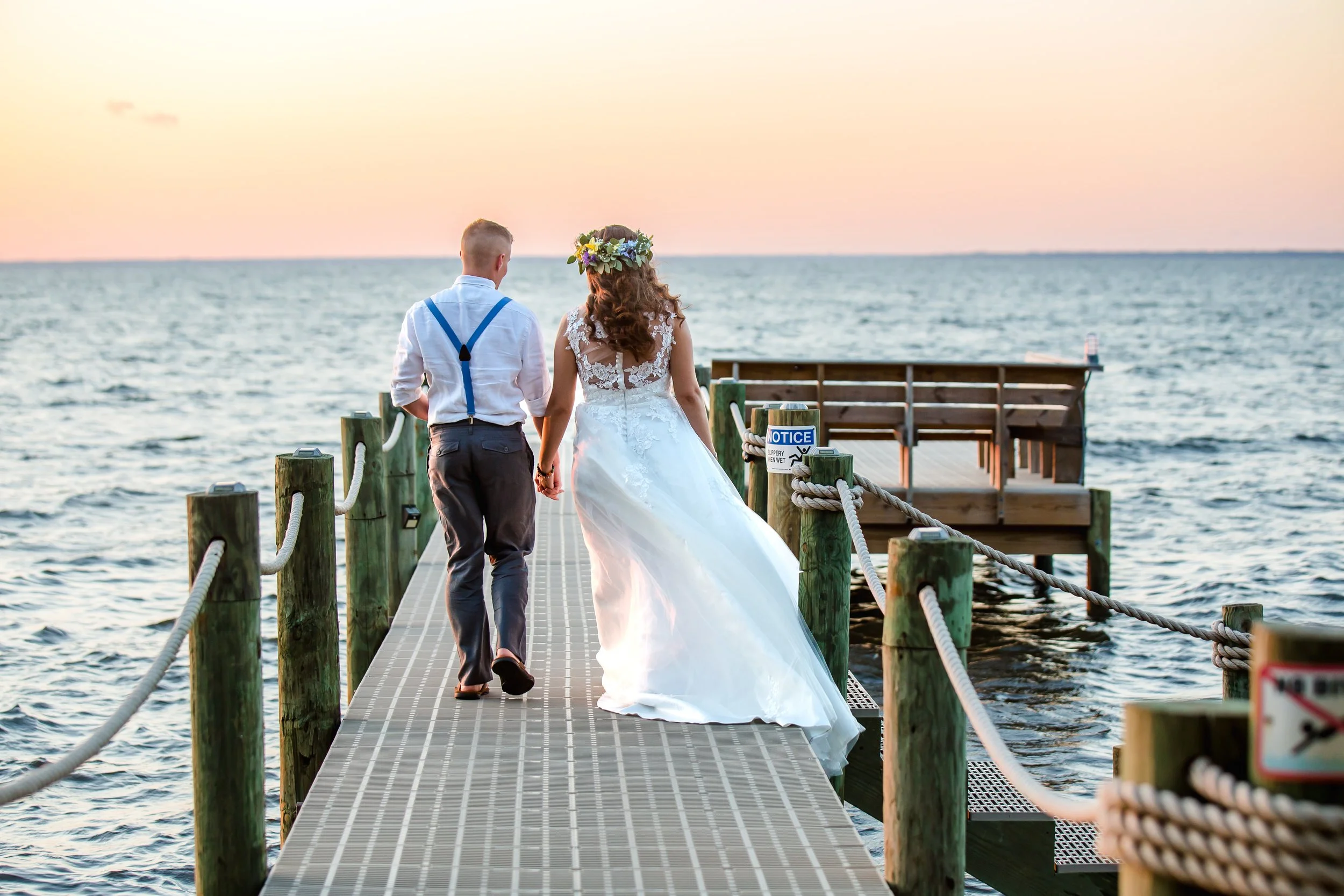 Bride and groom walking on a dock towards a sun set lit sky photo taken by St. Augustine and Jacksonville beach photographer