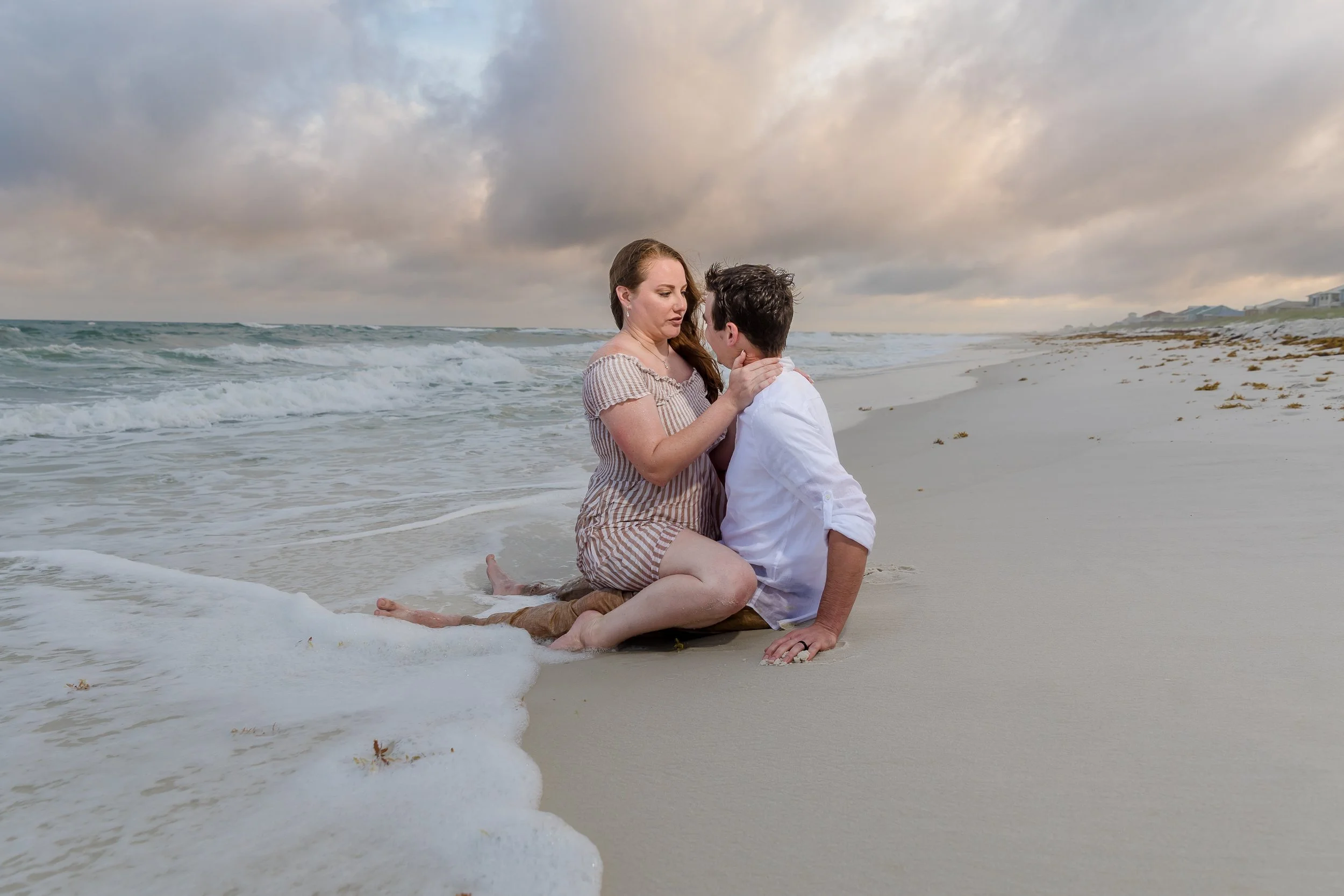 A couple embrace each other with waves crashing around them Image taken by Jacksonville beach and St. Augustine wedding photographer
