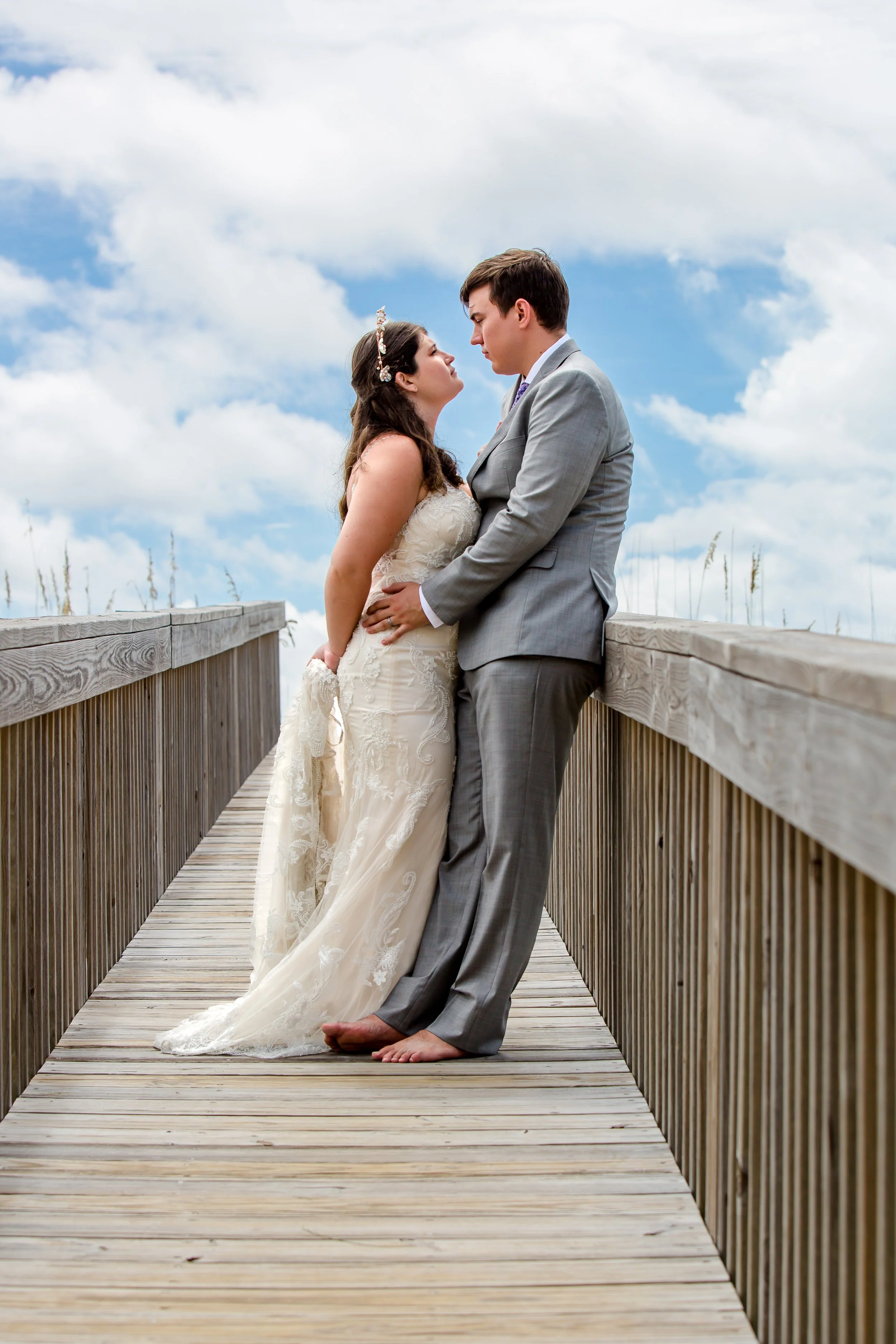 Bride and groom embrace on a boardwalk leading to navarre beach taken by Jacksonville beach and St. Augustine Florida Photographer