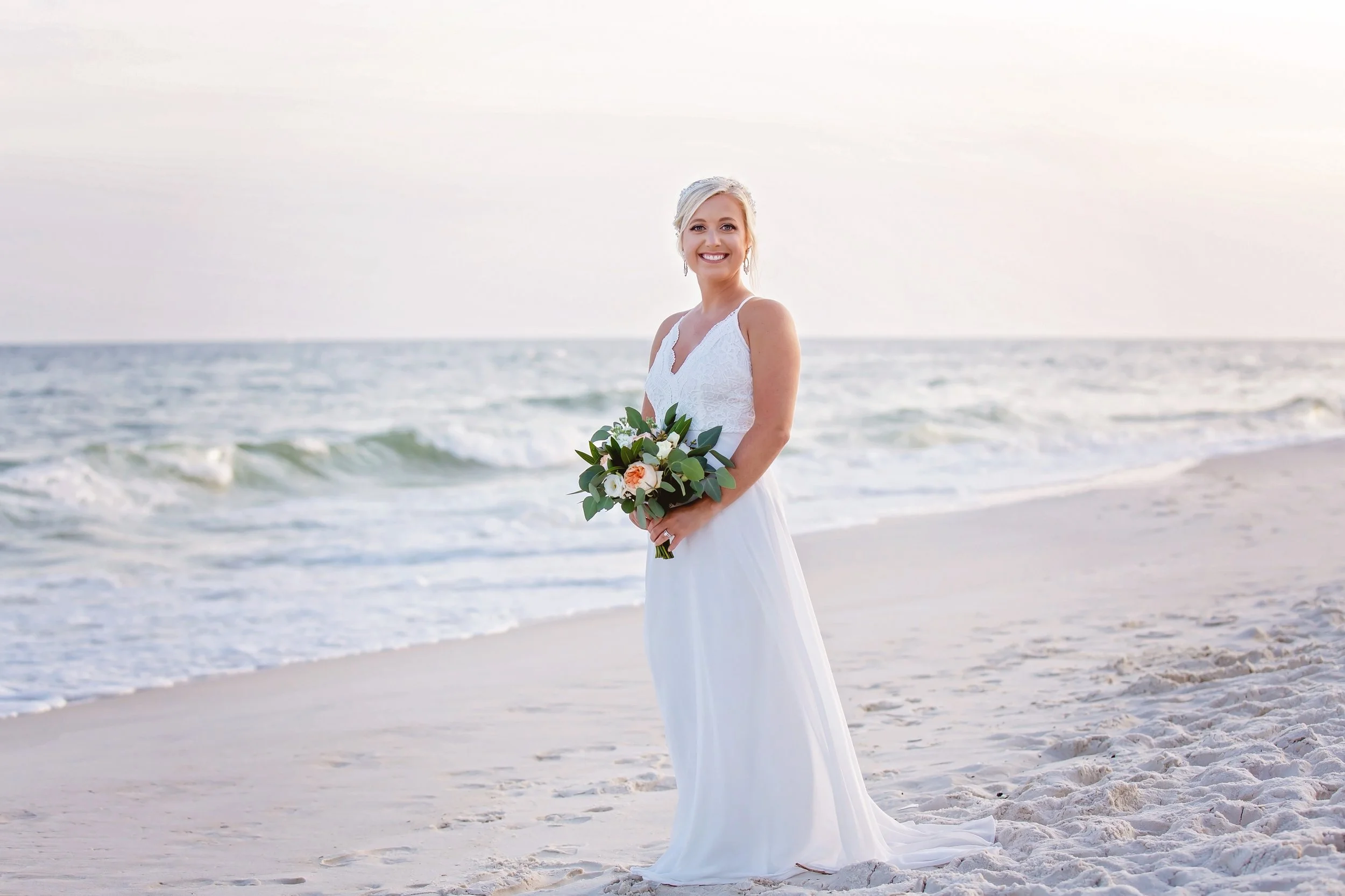 The stunning bride posing for her bridal portraits on the beautiful white sand beach in orange beach alabama