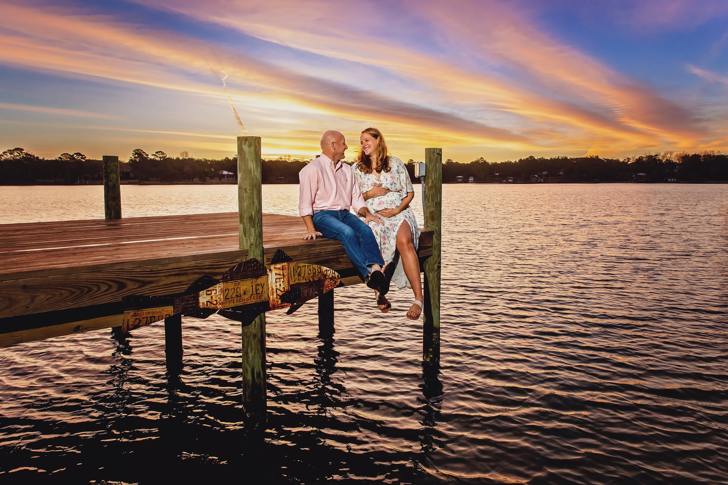 pregnancy pictures with the couple sitting on a dock in Jacksonville beach Florida
