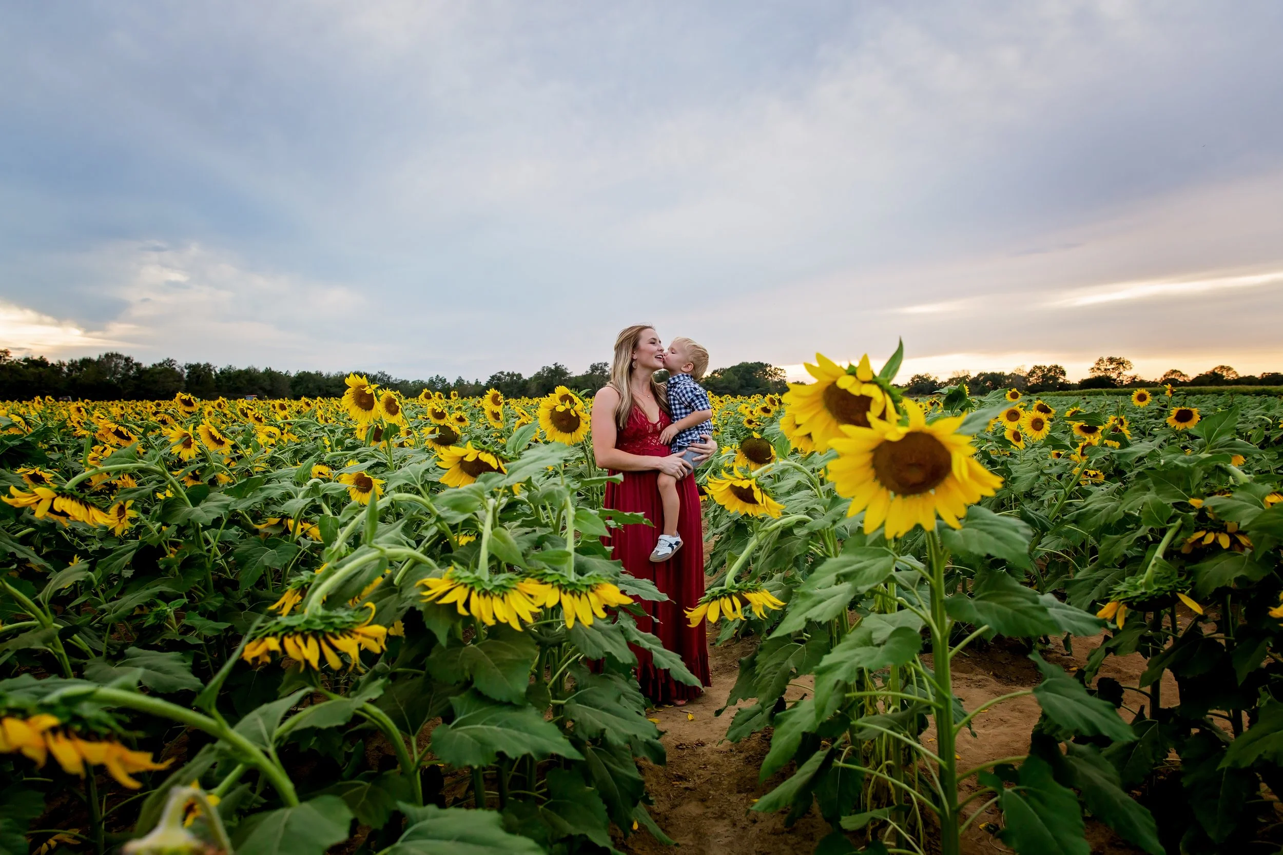 A picture of a mom holding her son in the middle of a sunflower field in Jacksonville Florida
